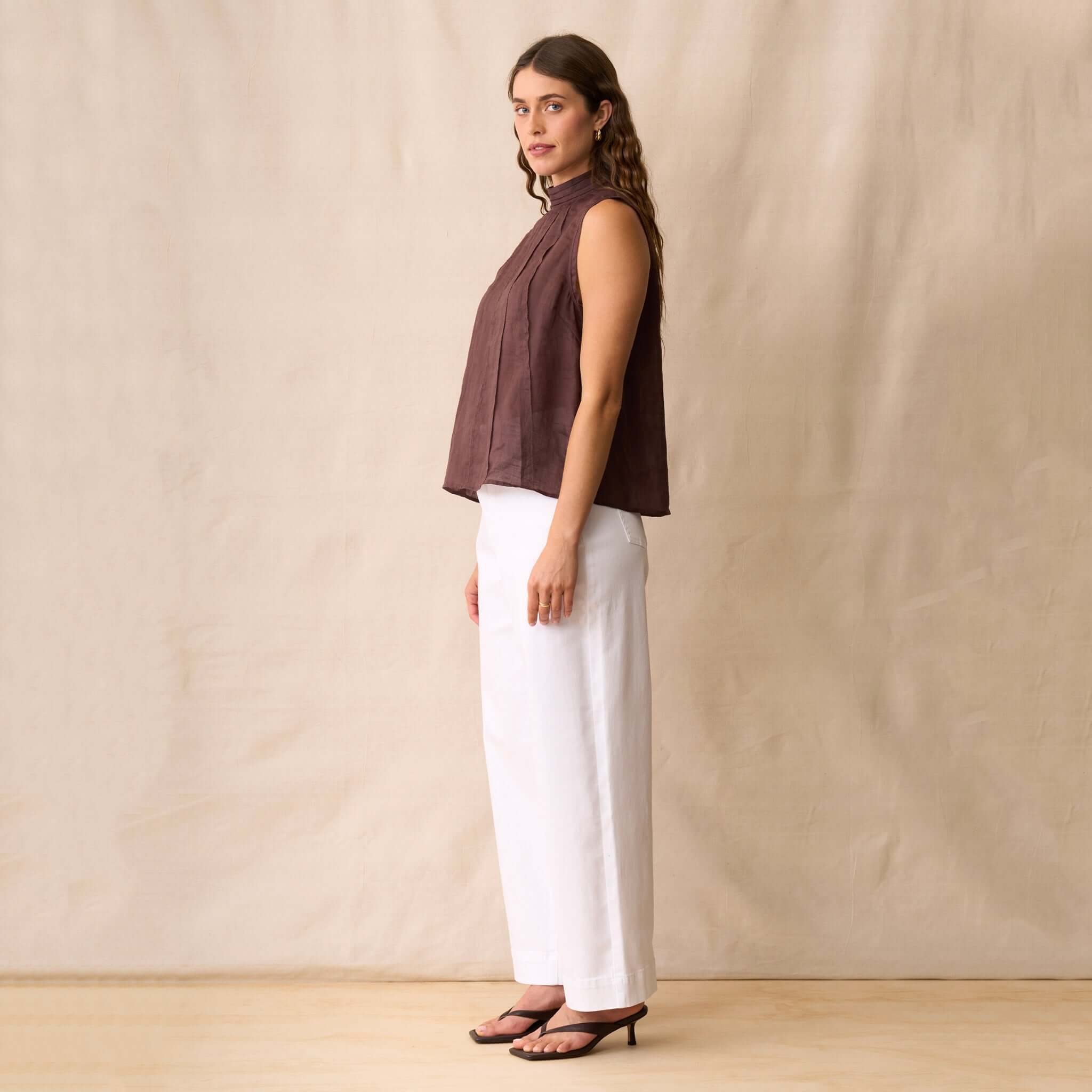 Neris Phoebe Top - Mahogany shown on model with white wide-leg pants against a neutral background.