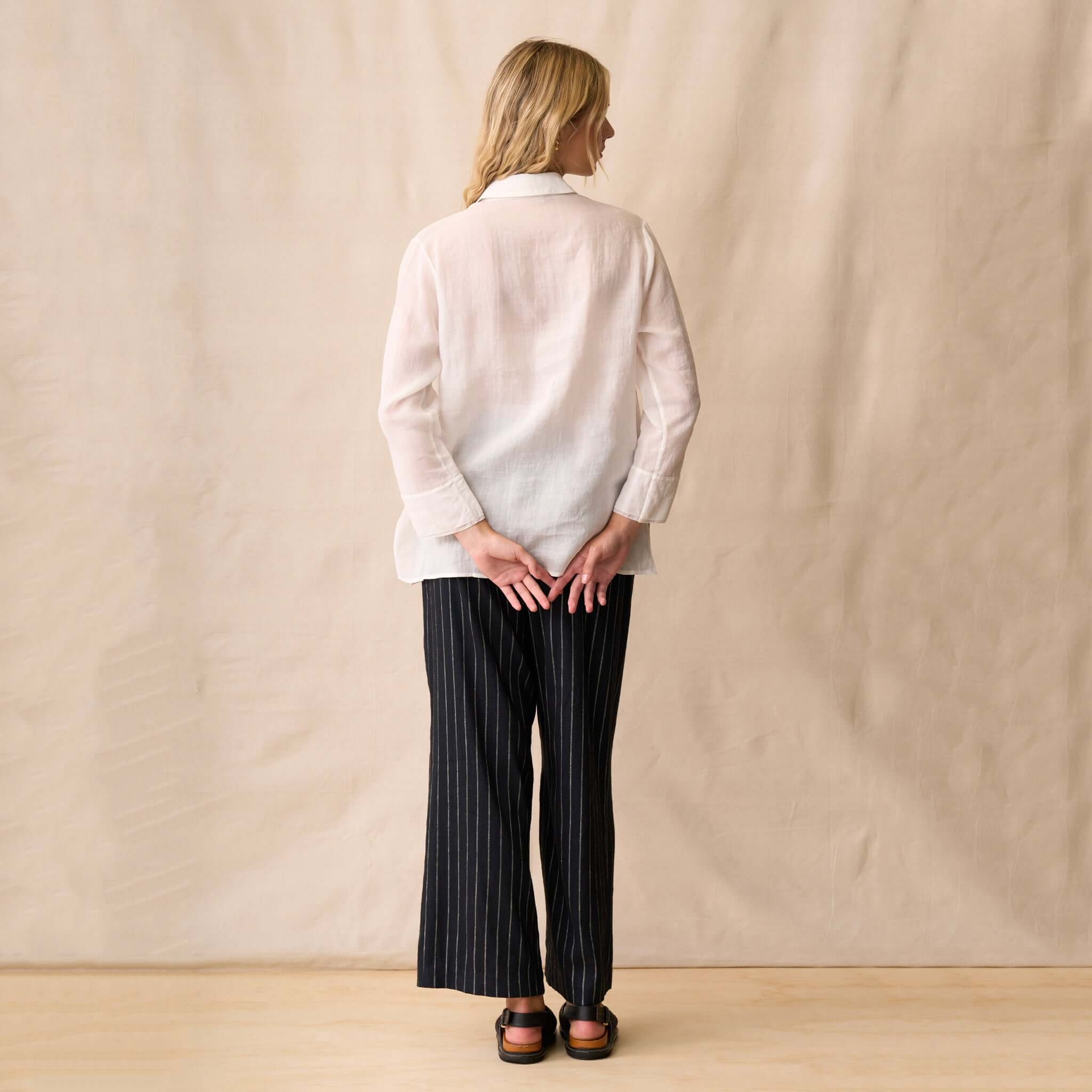 Neris Phoebe Top - White worn from the back, paired with striped pants in a casual setting.