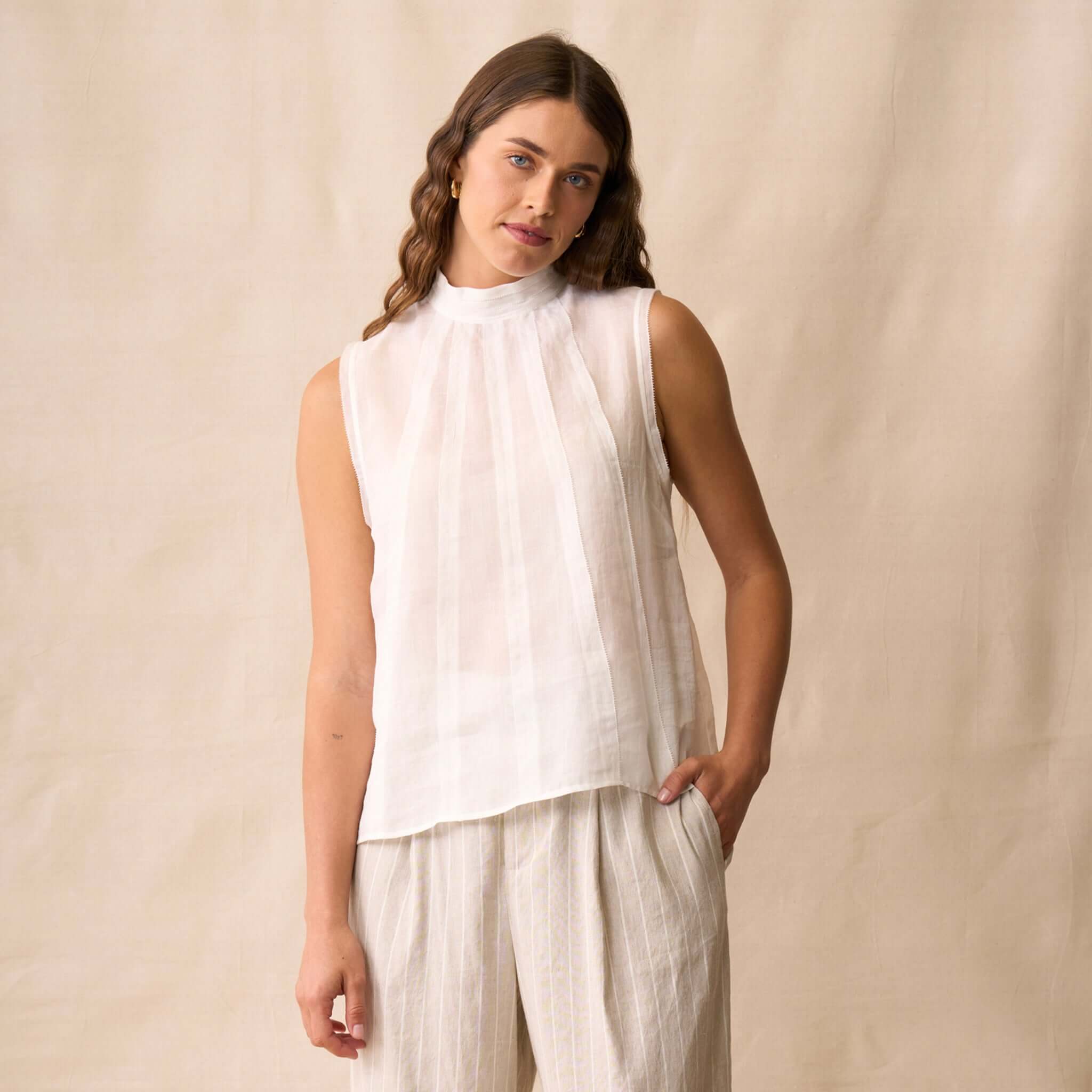 Neris Phoebe Top - White shown on model, featuring a sleeveless design and pleated neckline, perfect for warm weather.
