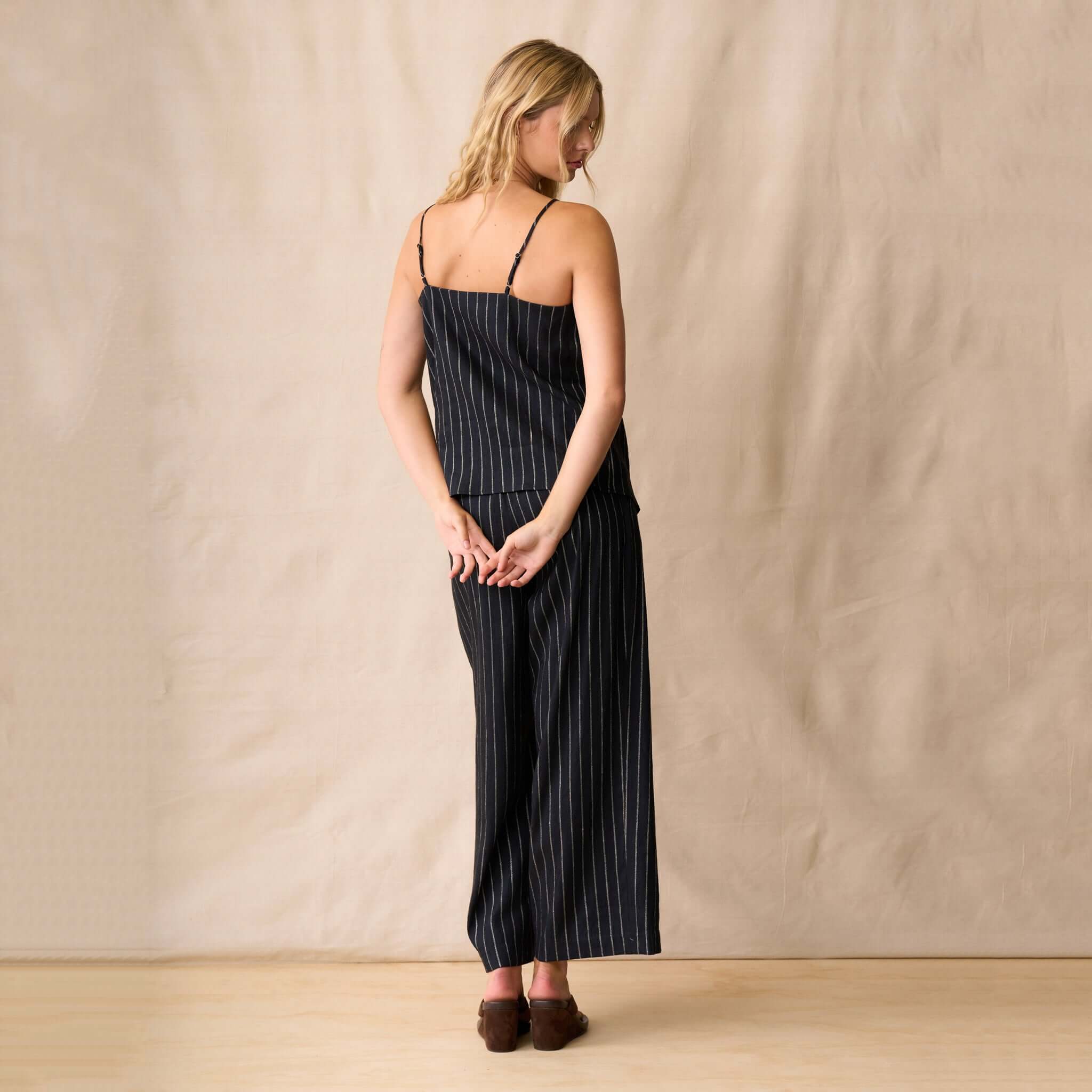 Model wearing the Neris Sloane Cami - Midnight, showcasing its flowing design and vertical stripes from the back.