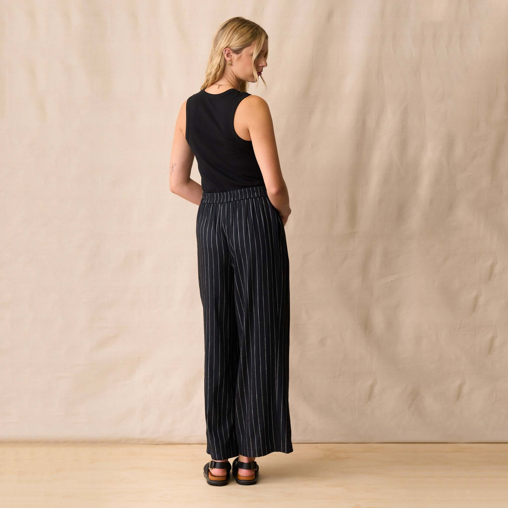 Model wearing Neris Sloane Trouser - Midnight, back view showcasing relaxed tailoring and metallic pinstripes.