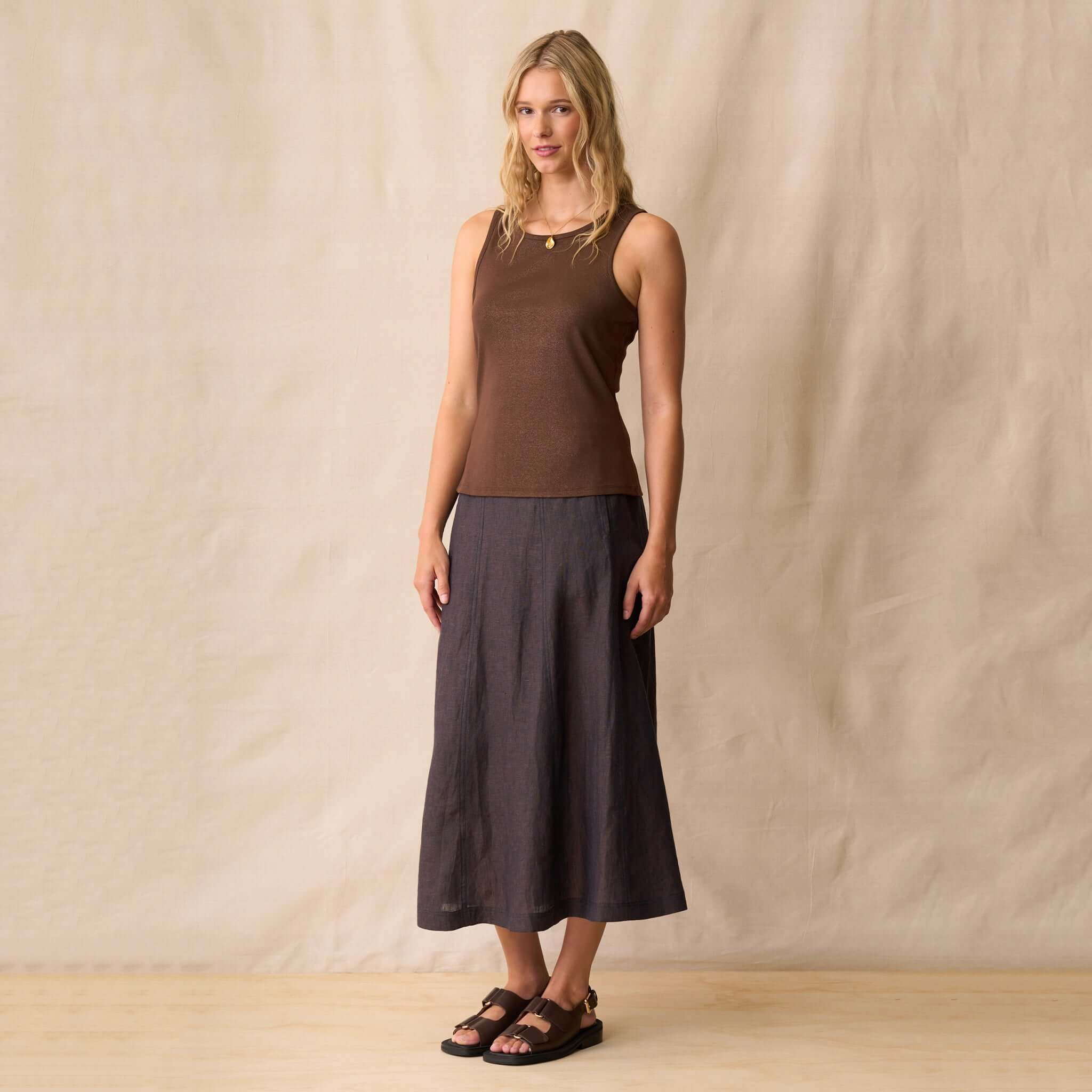Model wearing the Neris Ziggy Tank - Copper, a sleeveless top with a metallic shimmer and a high neckline.
