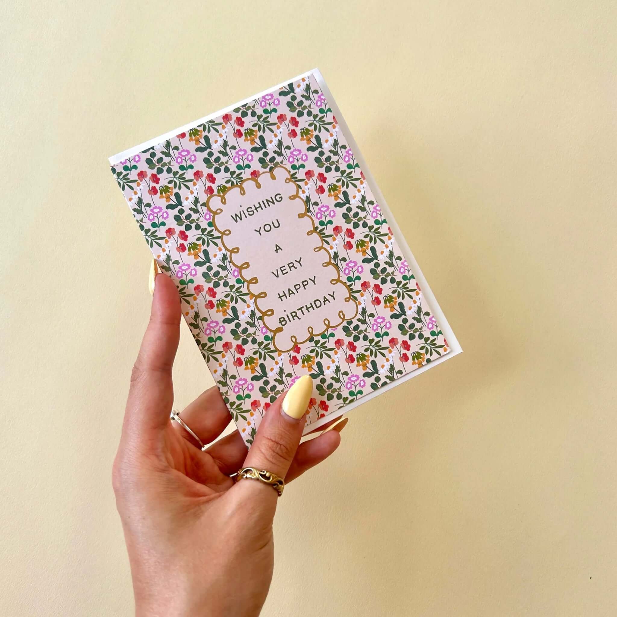 Noi Publishing Card - Ditsy Floral Fields Birthday in hand, featuring colorful floral design and gold foil text.