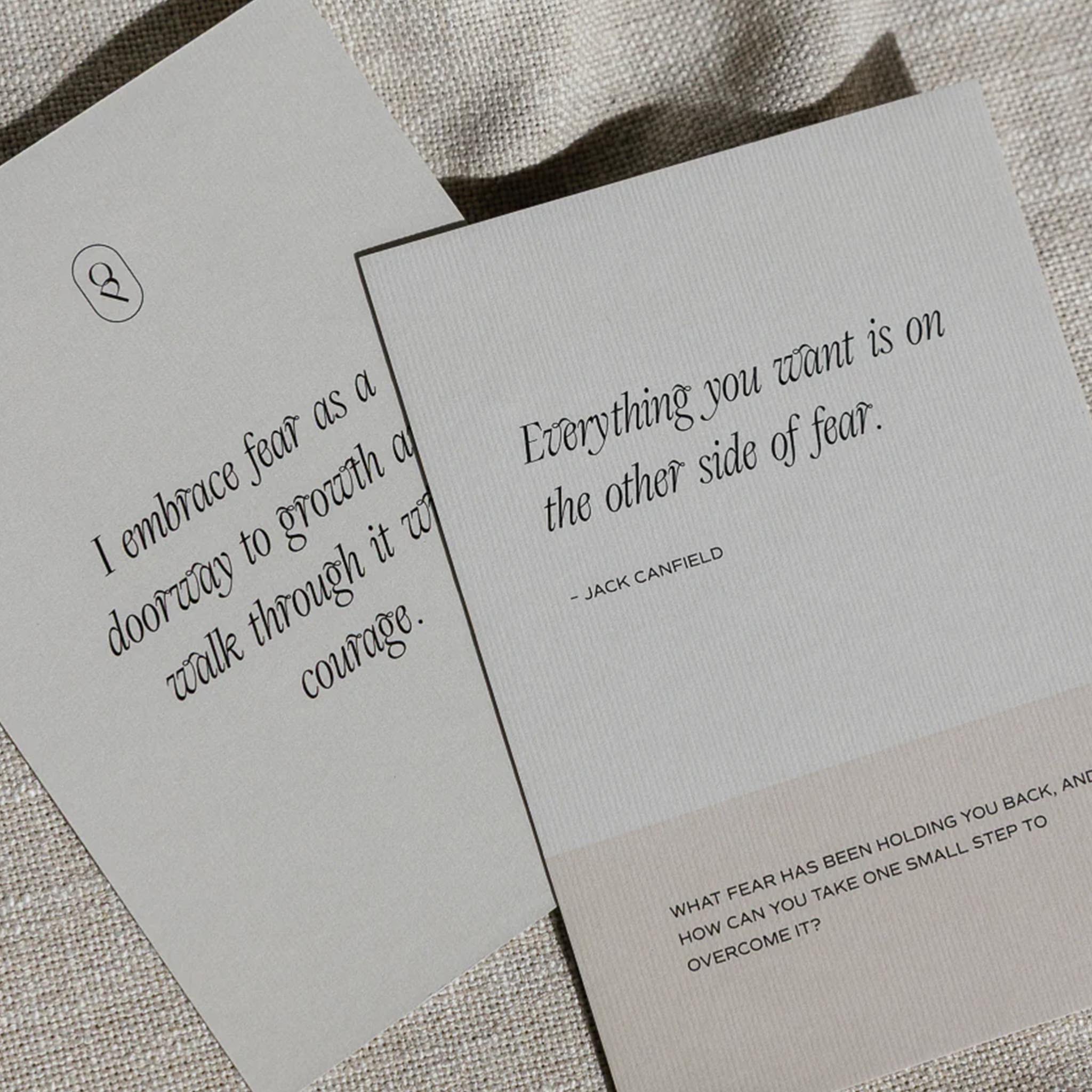 Two gray cards with motivational quotes on a textured surface