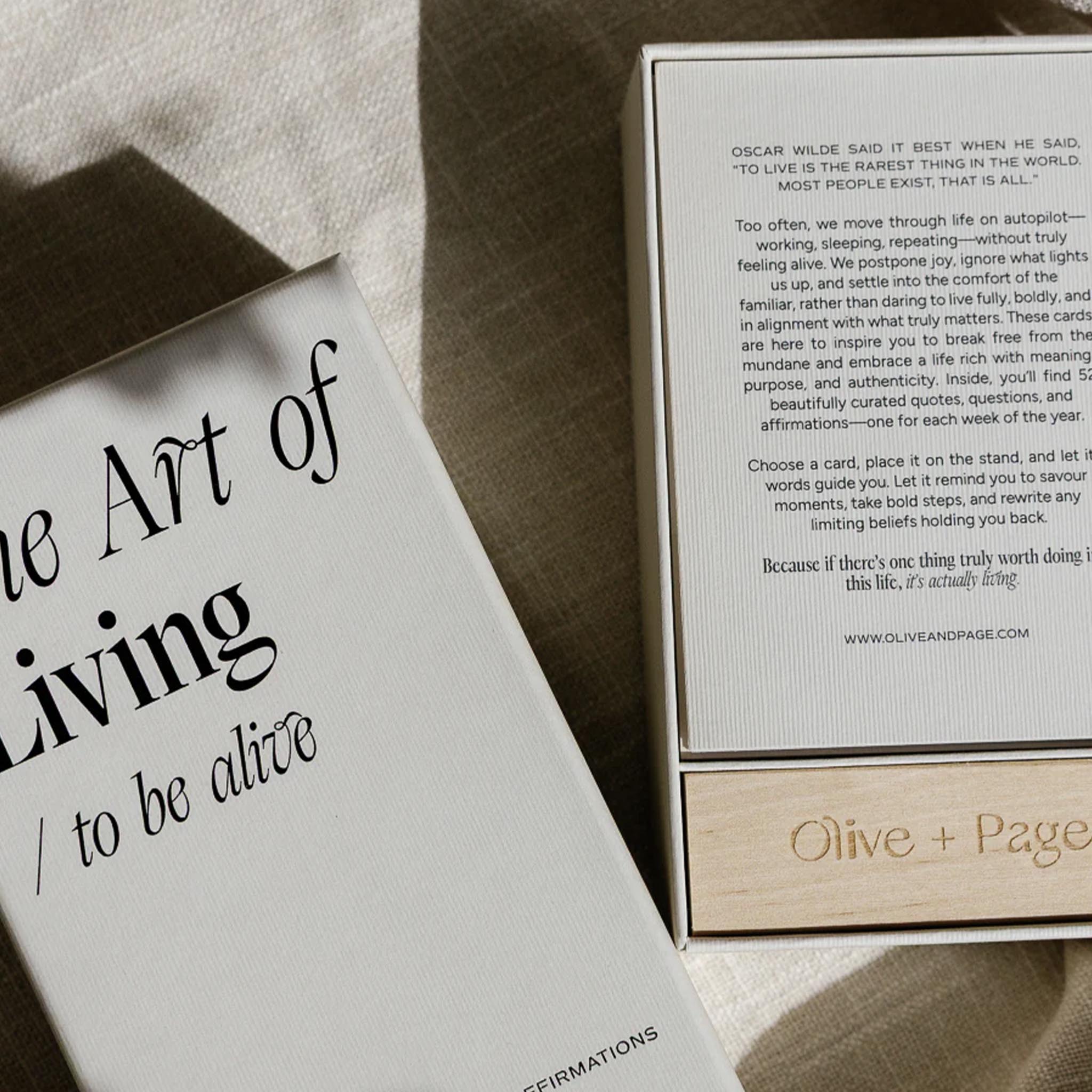 Cardbox with 'The Art of Living' book and Olive + Page packaging on a textured surface