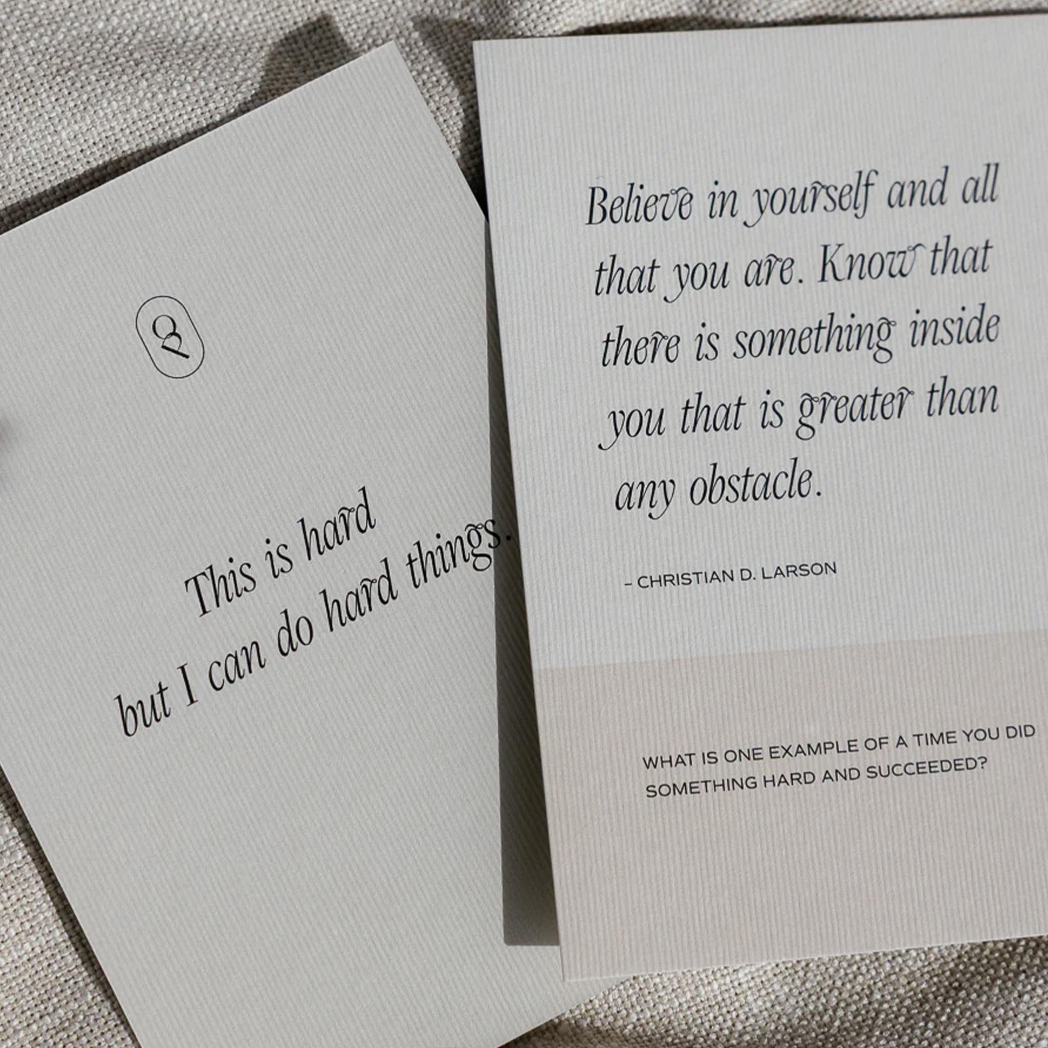 Two cards with motivational quotes on a textured surface