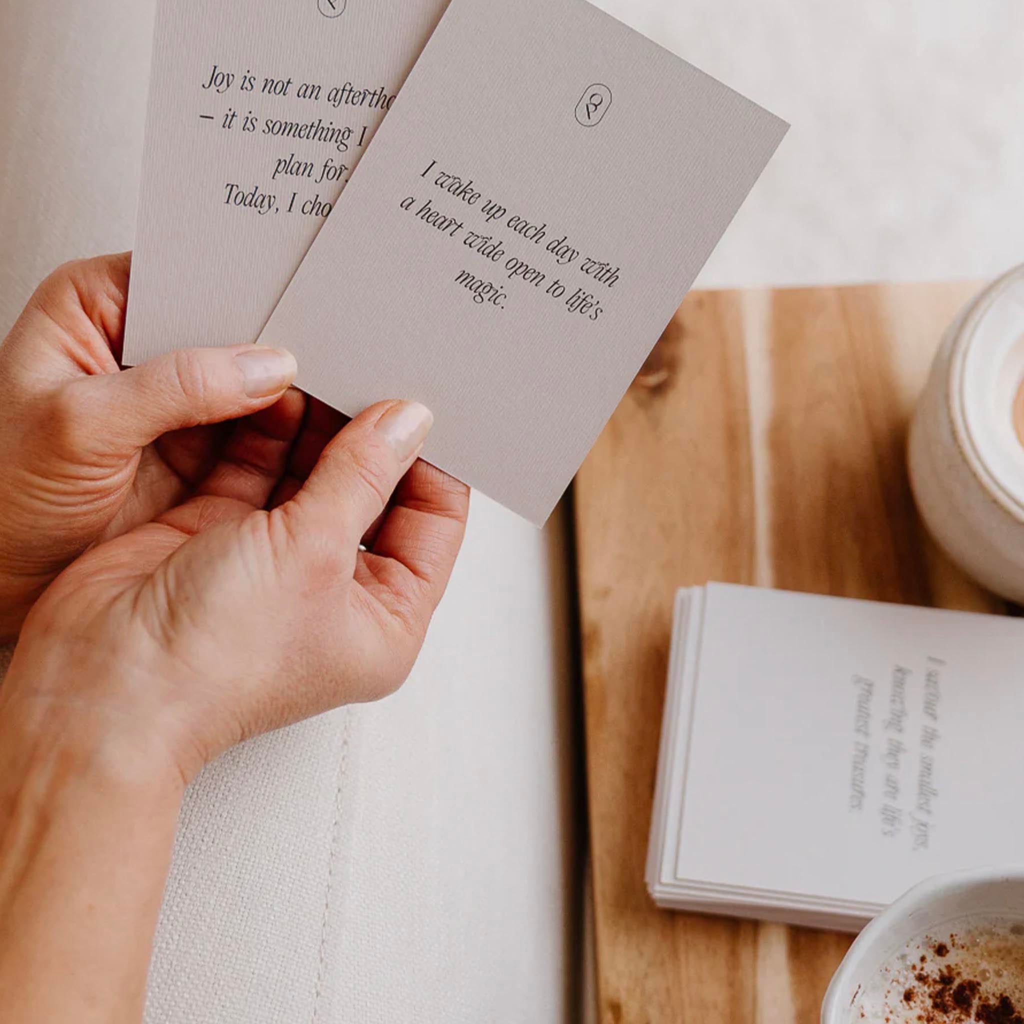 Hand holding a card with a quote, with a cup of coffee and book in the background