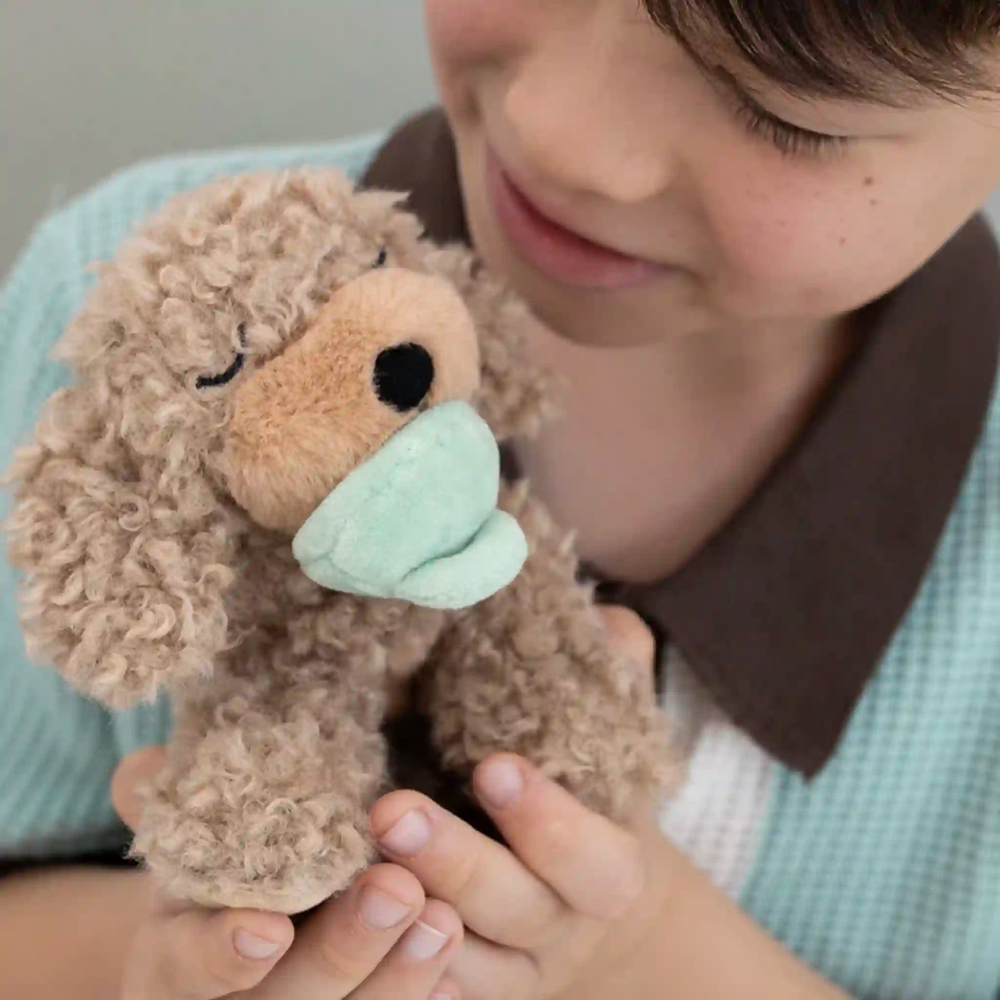 Child holding a plush toy with a face mask