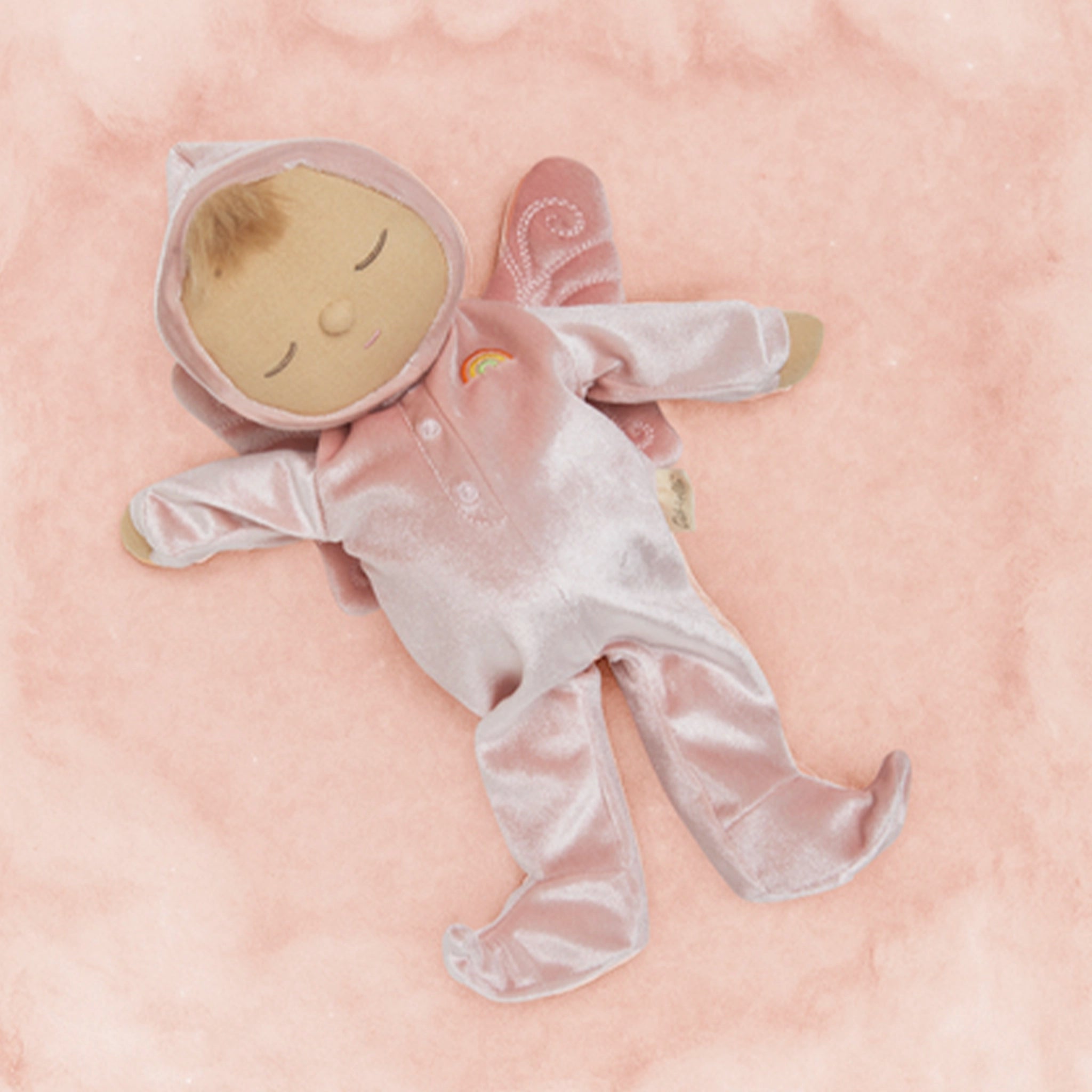 Baby doll in a pink outfit with a hood on a pink background