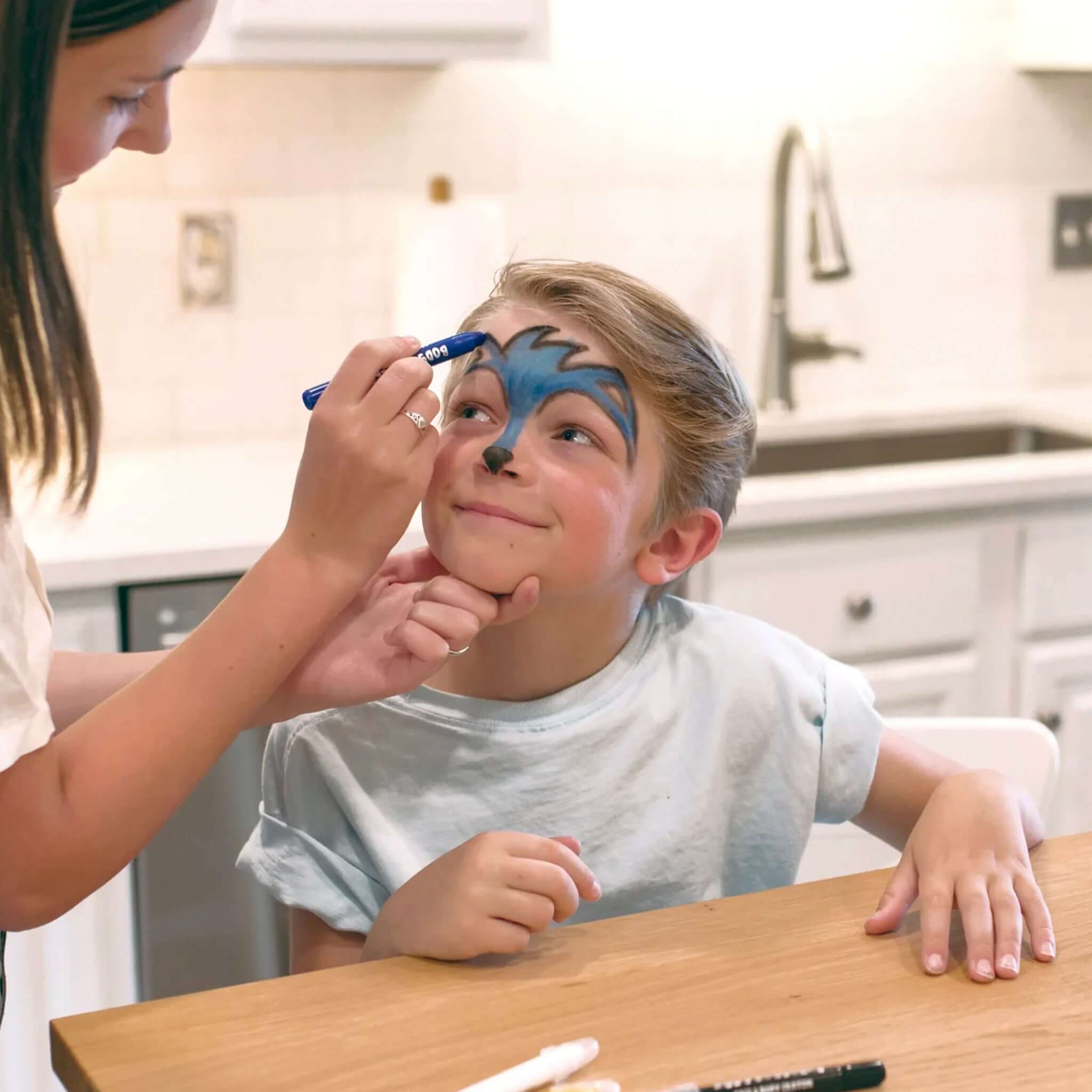 A child being painted with Ooly Face & Body Doodlers Crayons, showcasing creativity and fun during face painting.