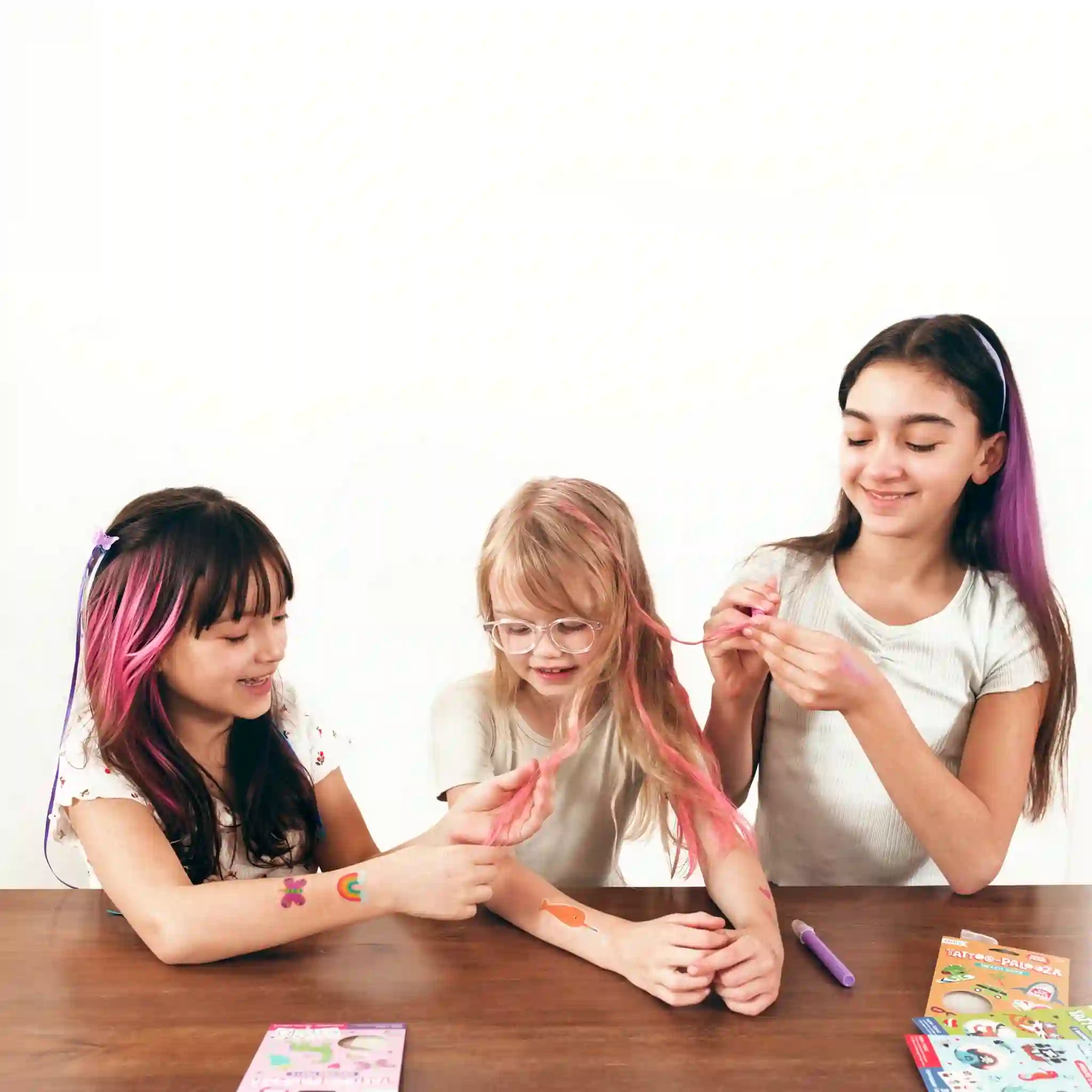 Three children with colorful hair sitting at a table, engaging in a hair-dyeing activity.