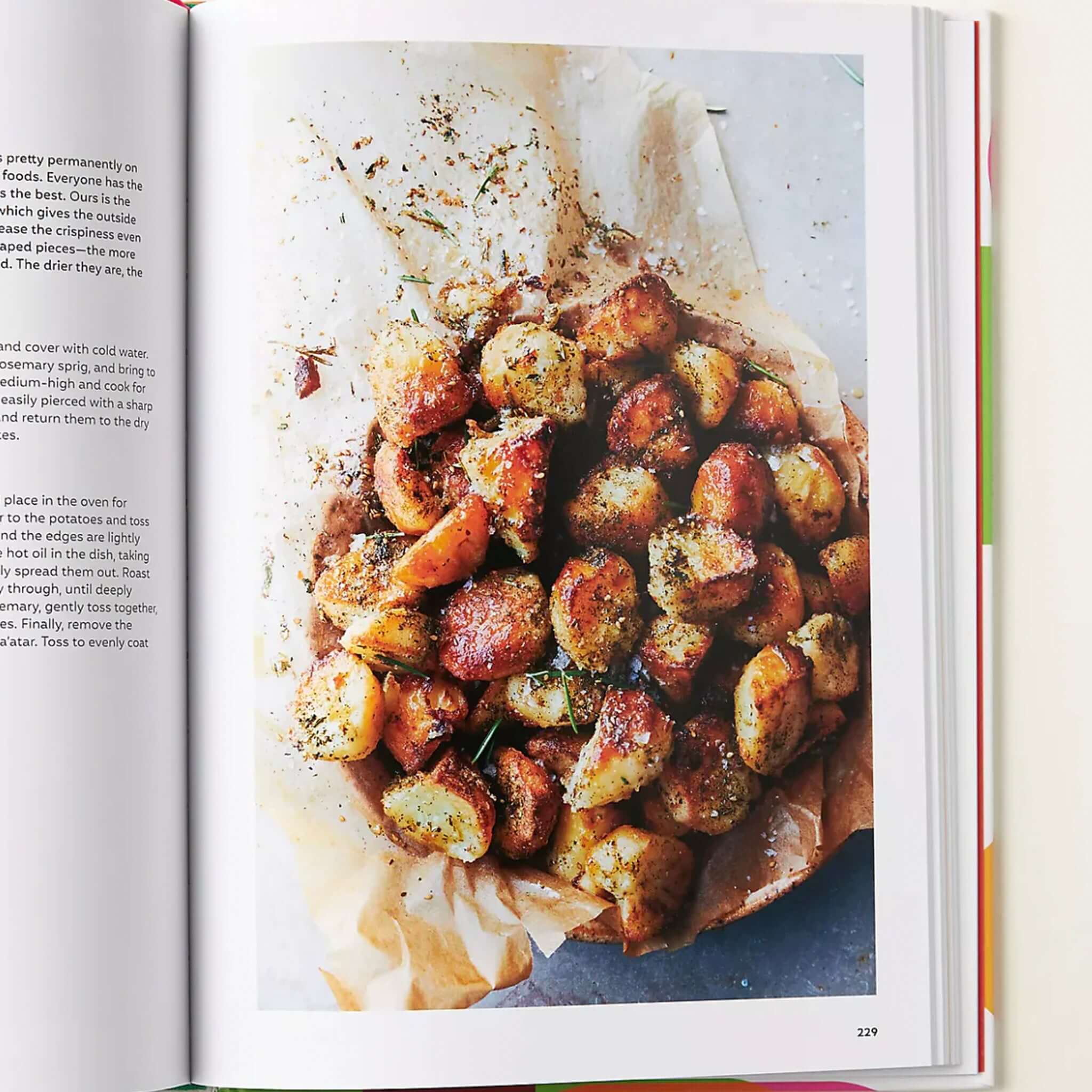 Alt Tag: Ottolenghi Comfort cookbook open to recipe page featuring crispy roasted potatoes on parchment, comfort food recipe photography