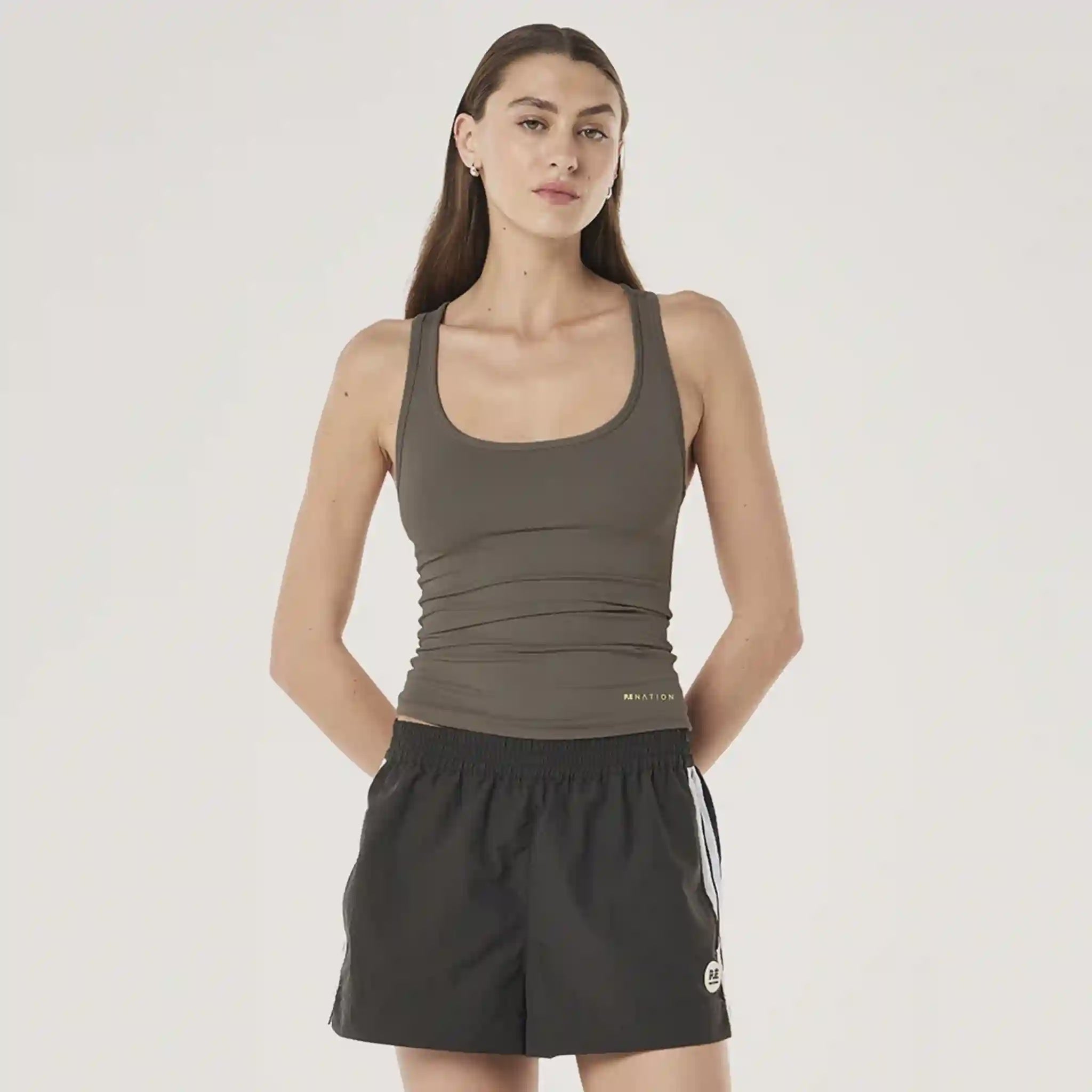 Woman wearing a green tank top and black shorts on a white background