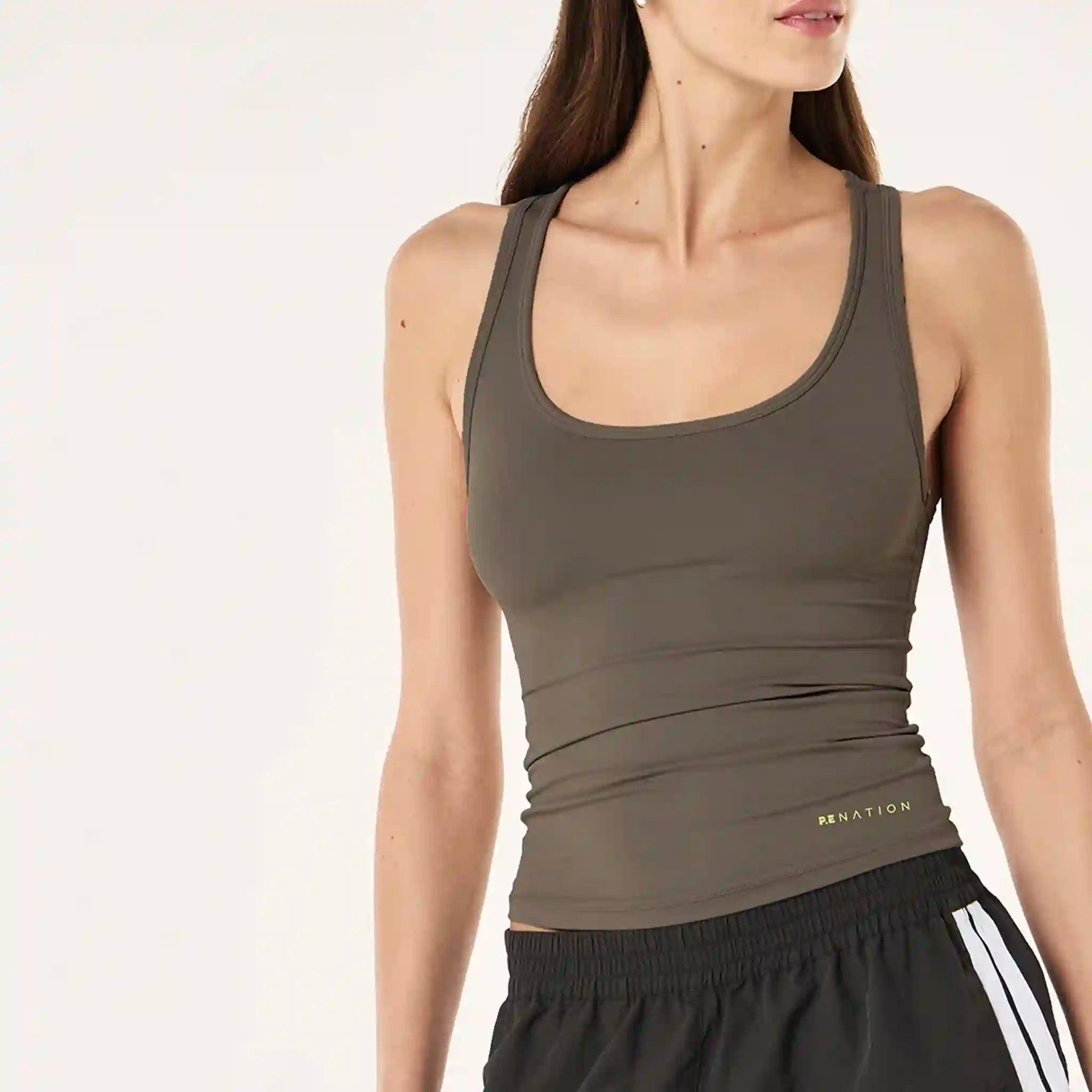 Woman wearing a brown tank top with a visible brand logo on a white background