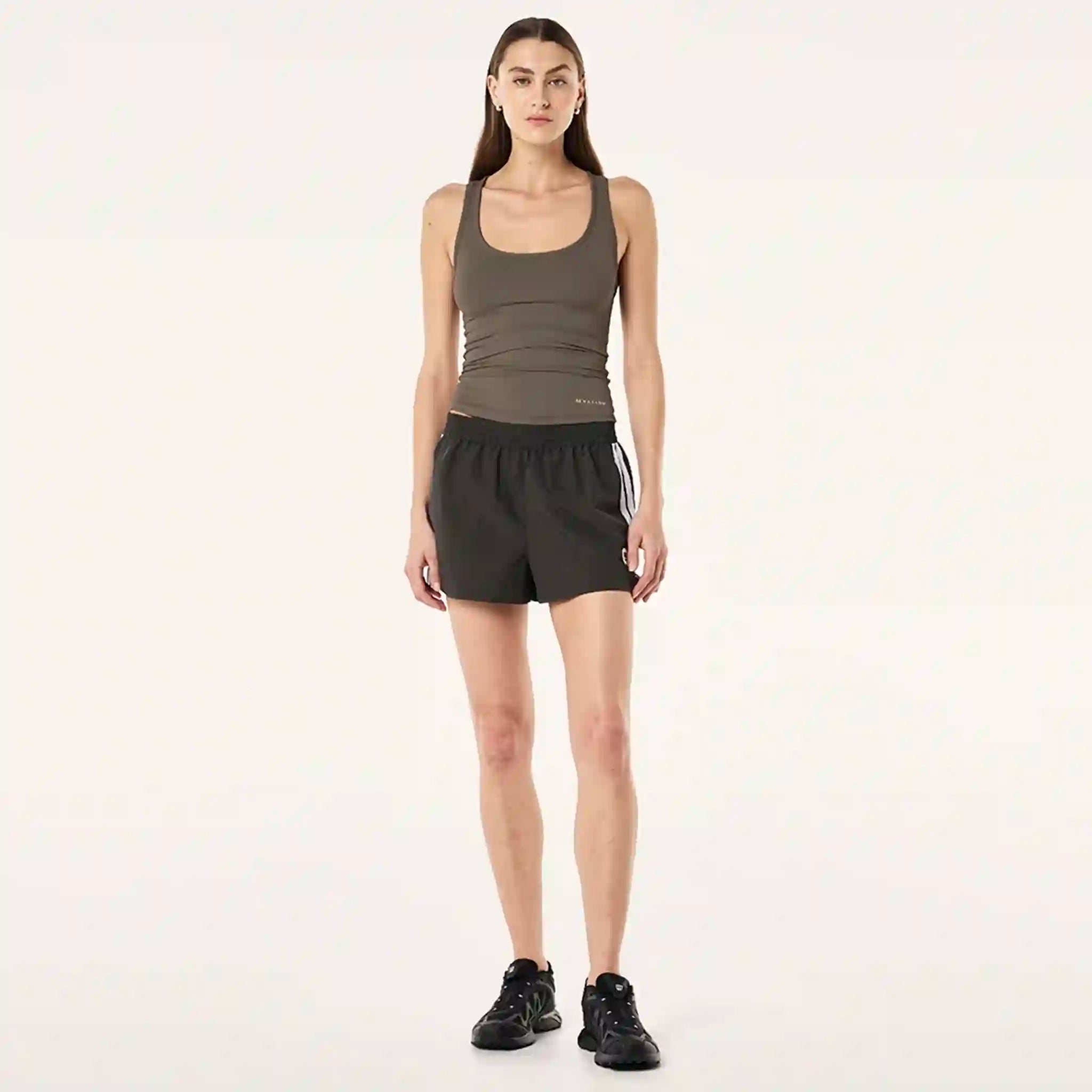 Woman wearing a green tank top and black shorts on a white background