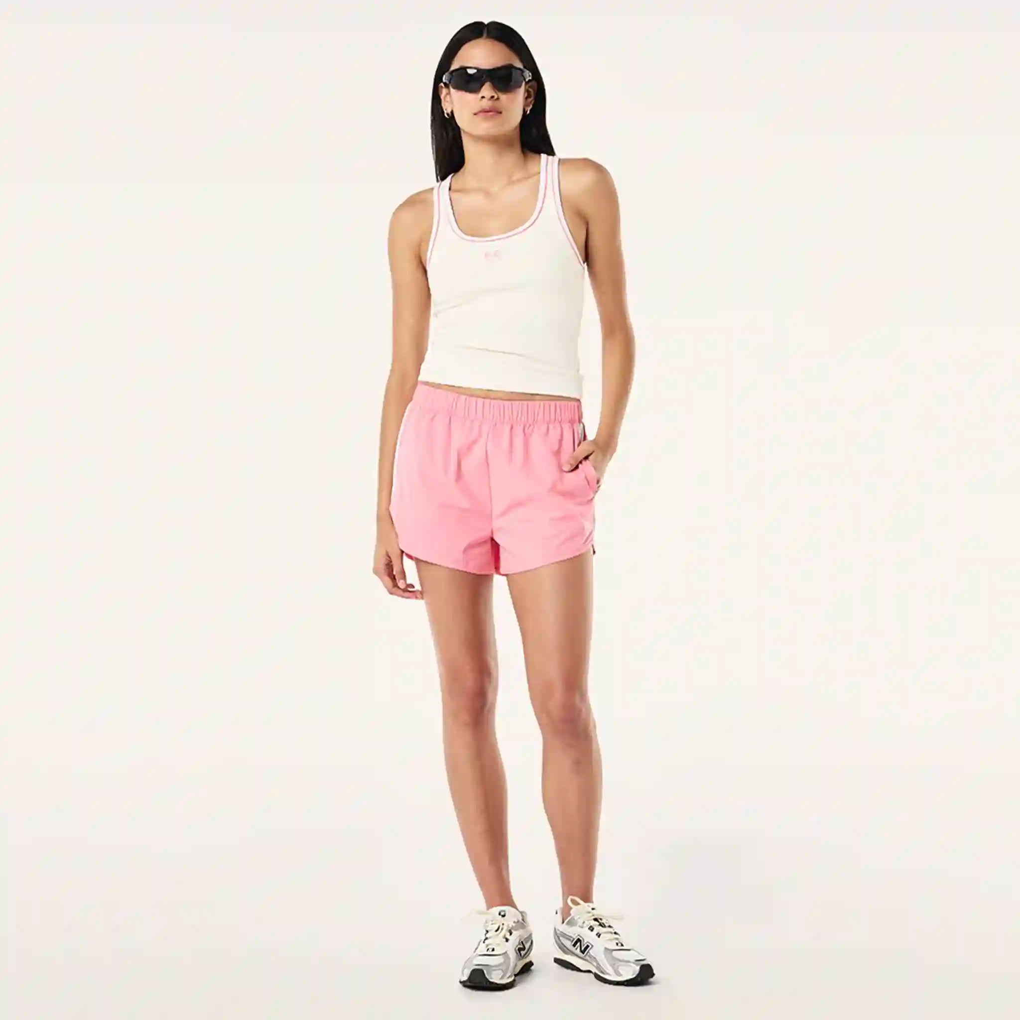 Woman wearing a white tank top and pink shorts on a white background
