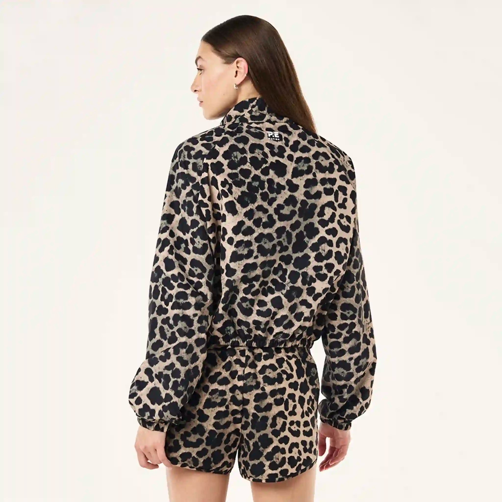 Person wearing a leopard print jacket and shorts on a plain background