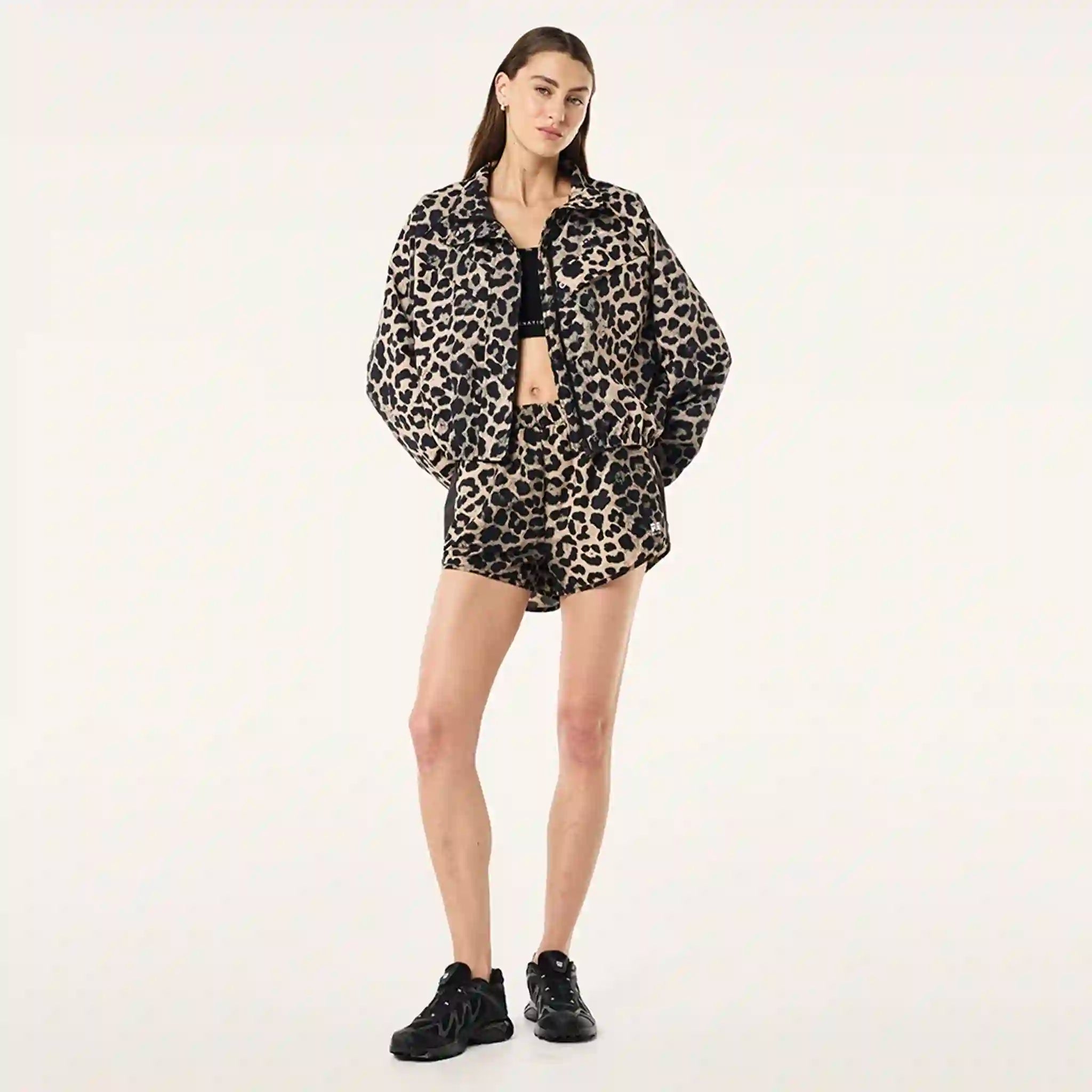 Person wearing a leopard print jacket and shorts on a plain background