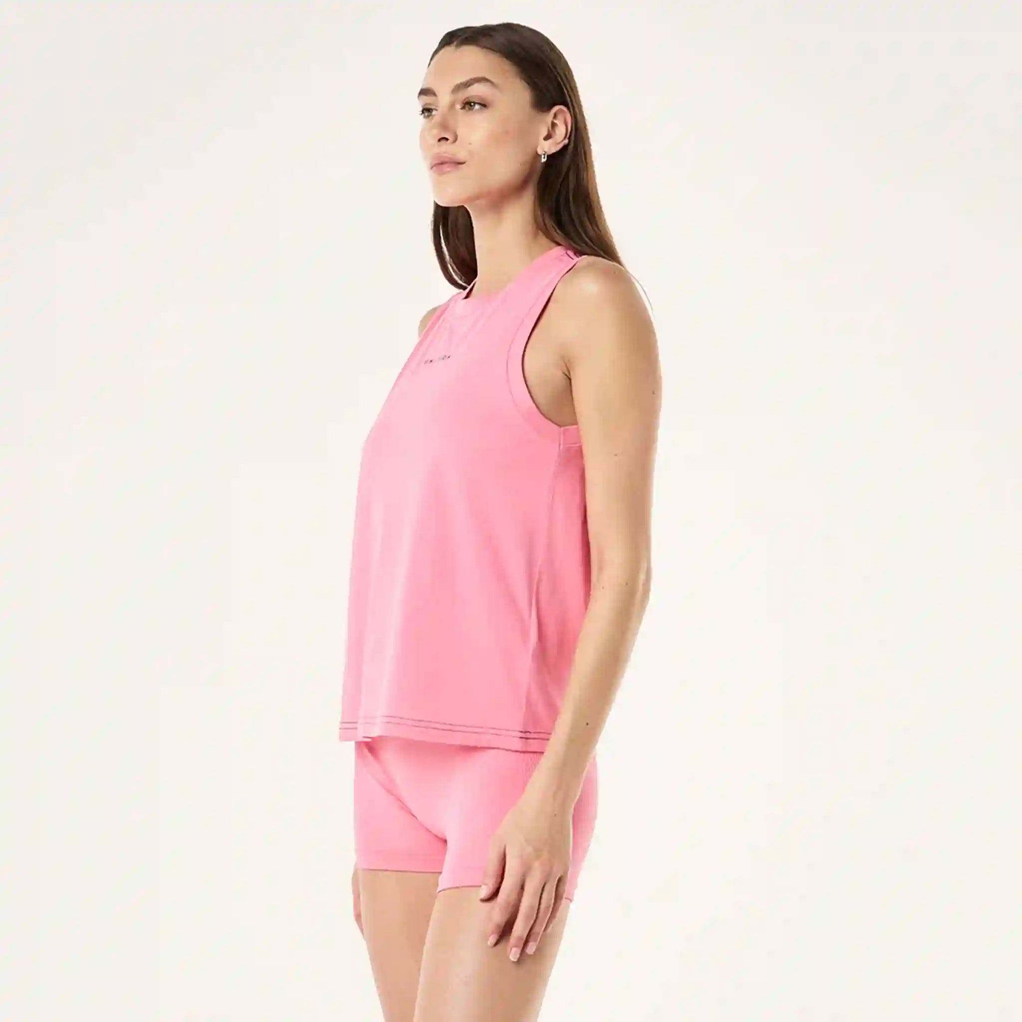 Woman wearing a pink sleeveless top and shorts on a white background