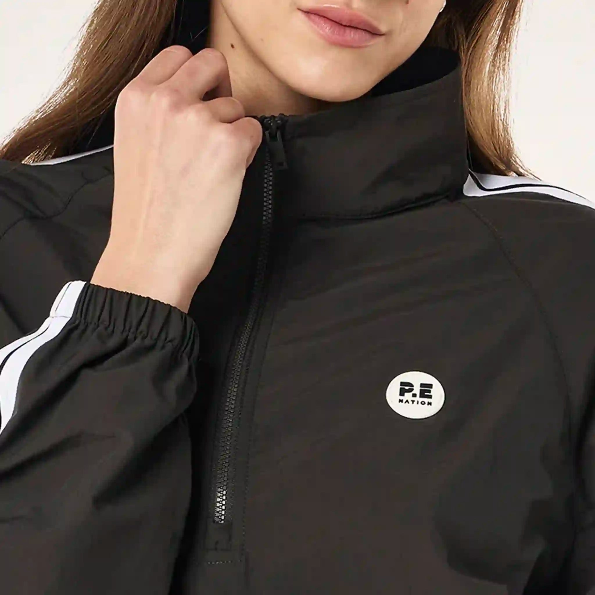 Person wearing a black jacket and shorts with white stripes on a light gray background