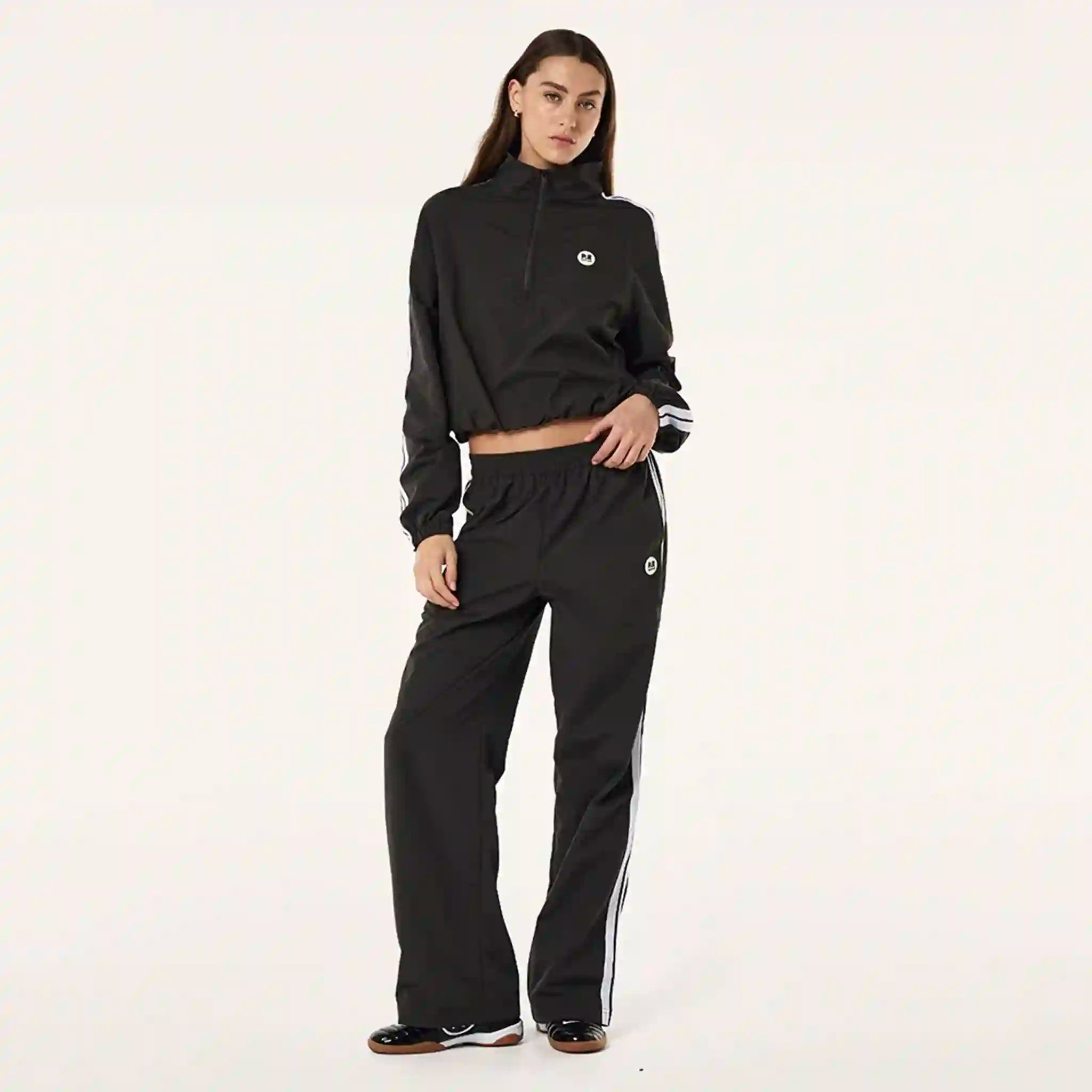 Person wearing a black tracksuit with white stripes on a white background