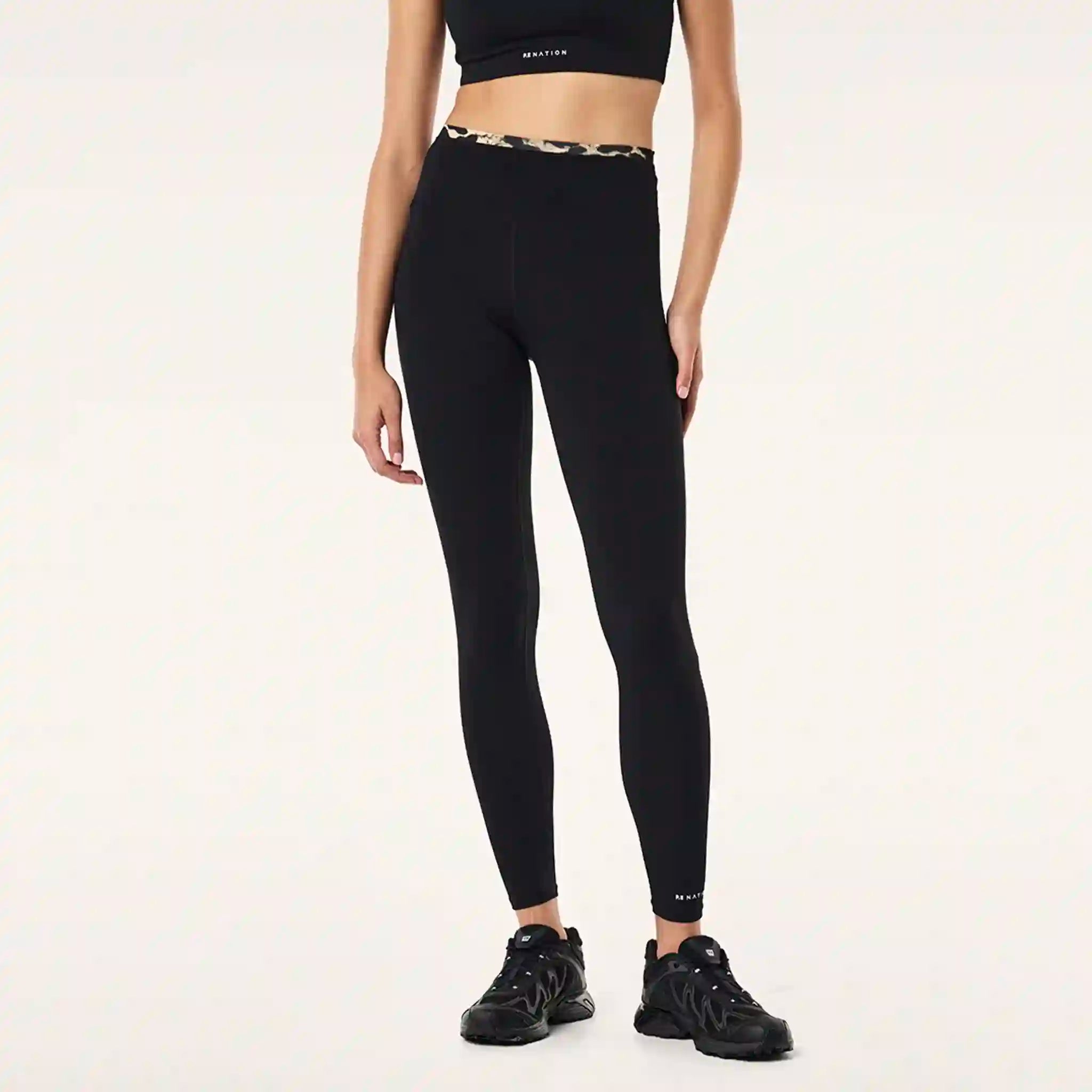 Person wearing black leggings and sports bra on a white background