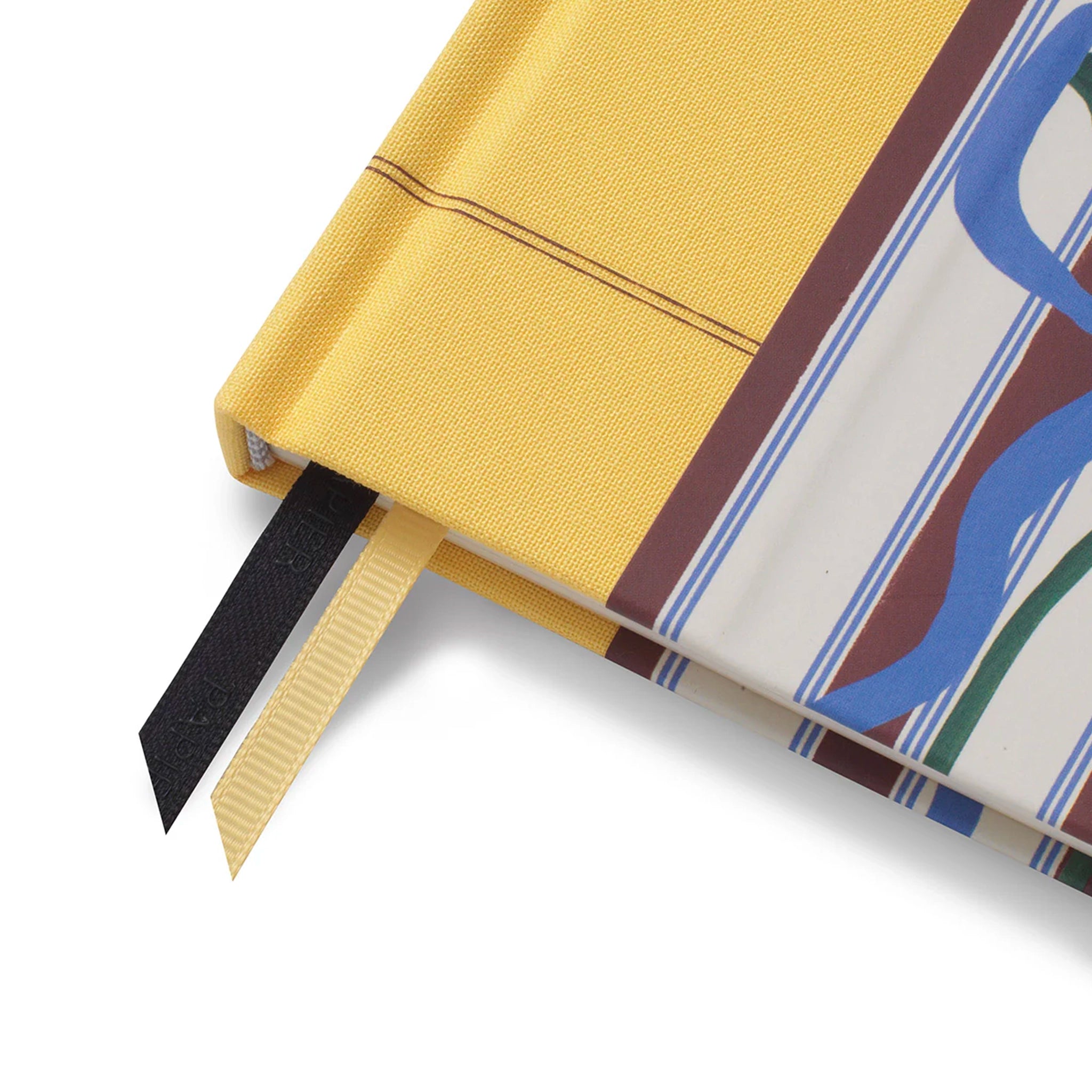 Close-up of a yellow fabric with a black ribbon and a patterned fabric with blue and green design.