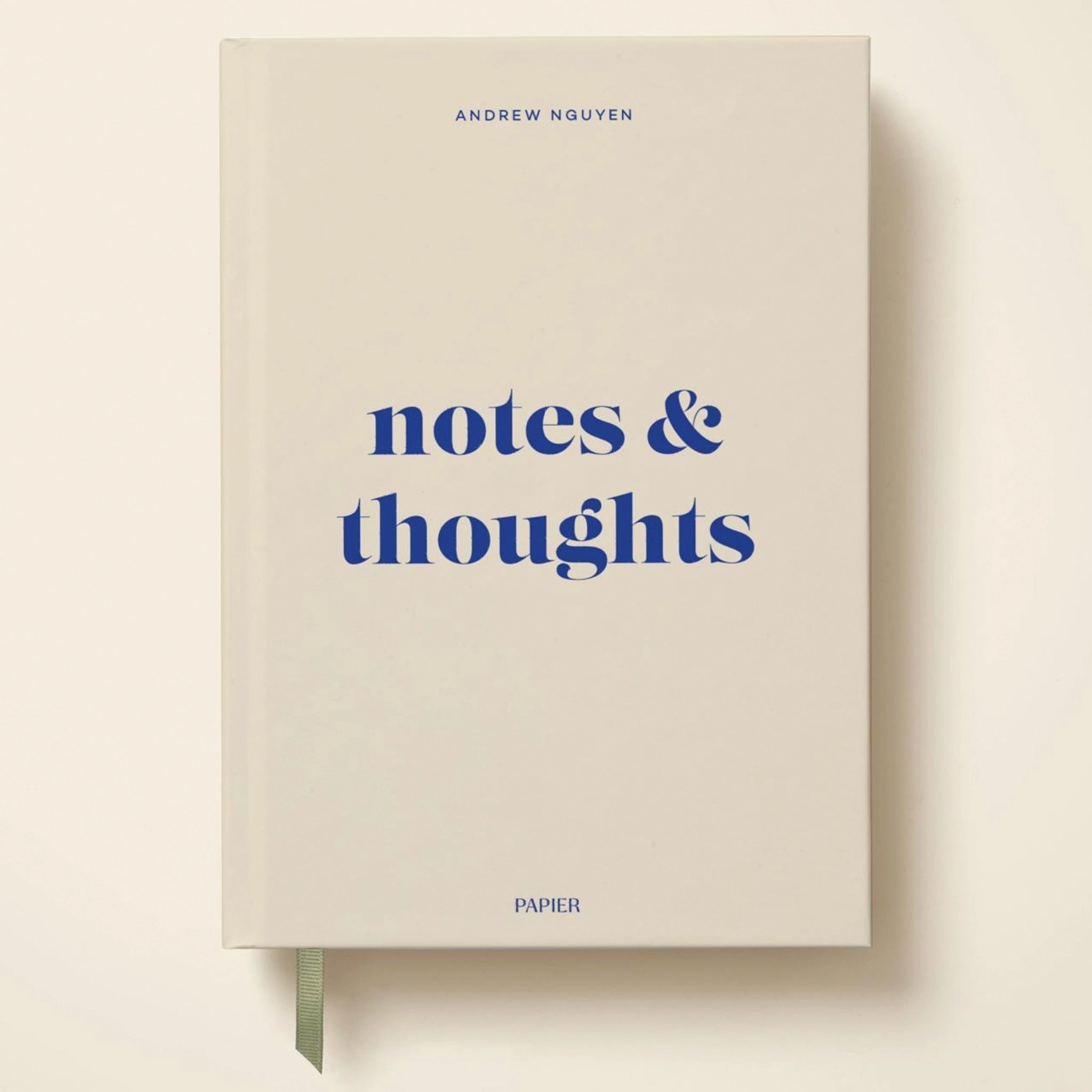 Beige notebook with 'notes & thoughts' text on a white background