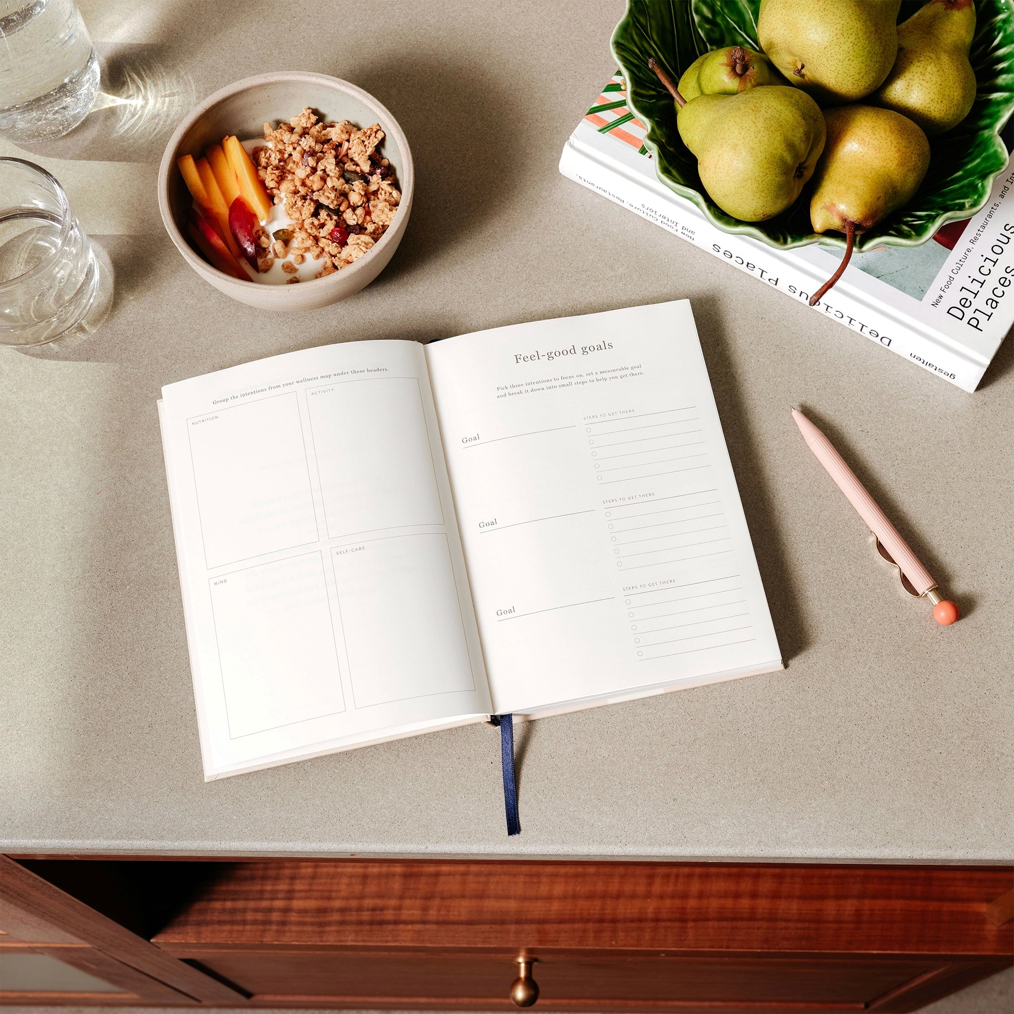 Open notebook on a table with pears, cereal, and a pencil