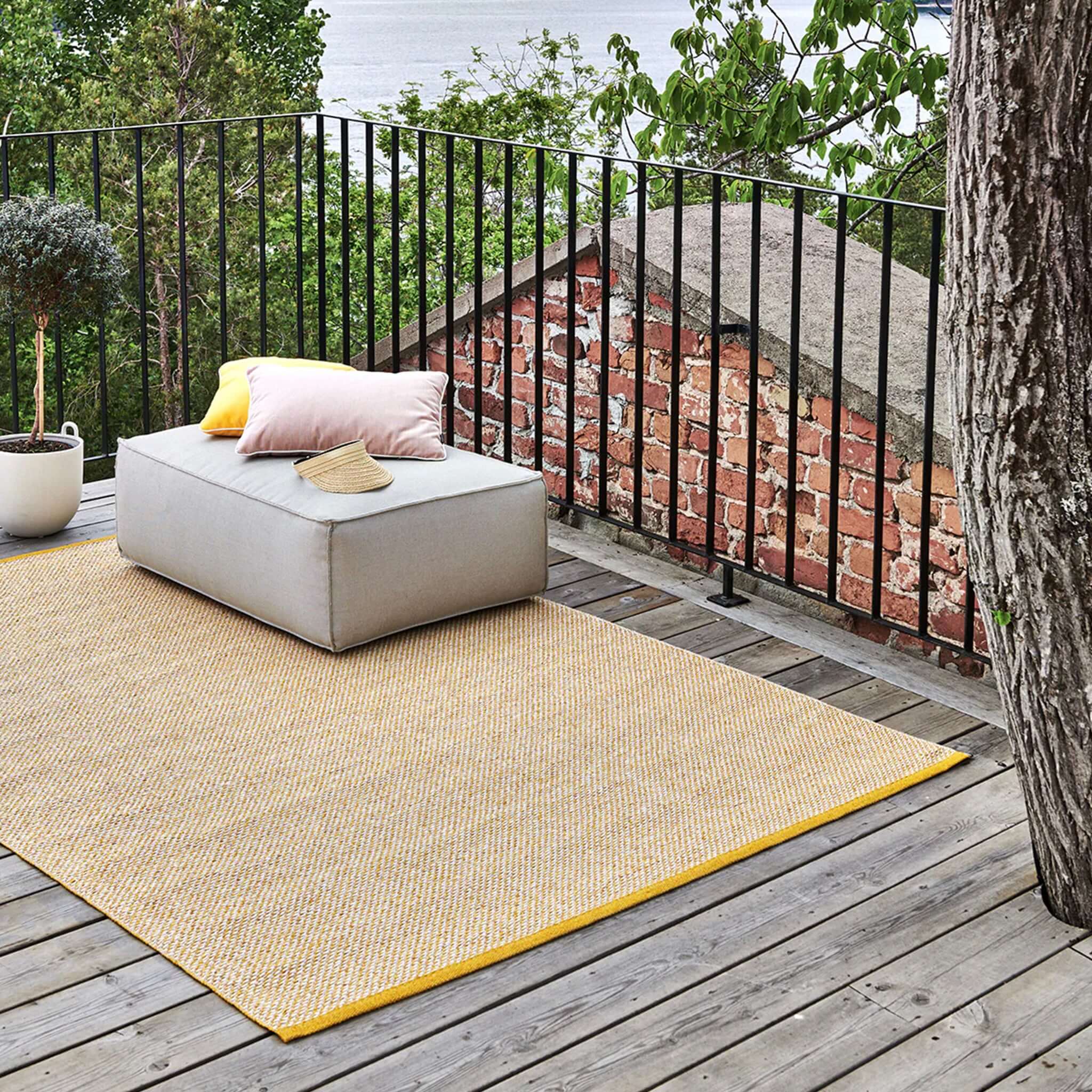 Alt Tag: Pappelina Sweden Effi Reversible Mat - Mustard on outdoor wooden deck, soft three-colour woven rug with hemmed edges