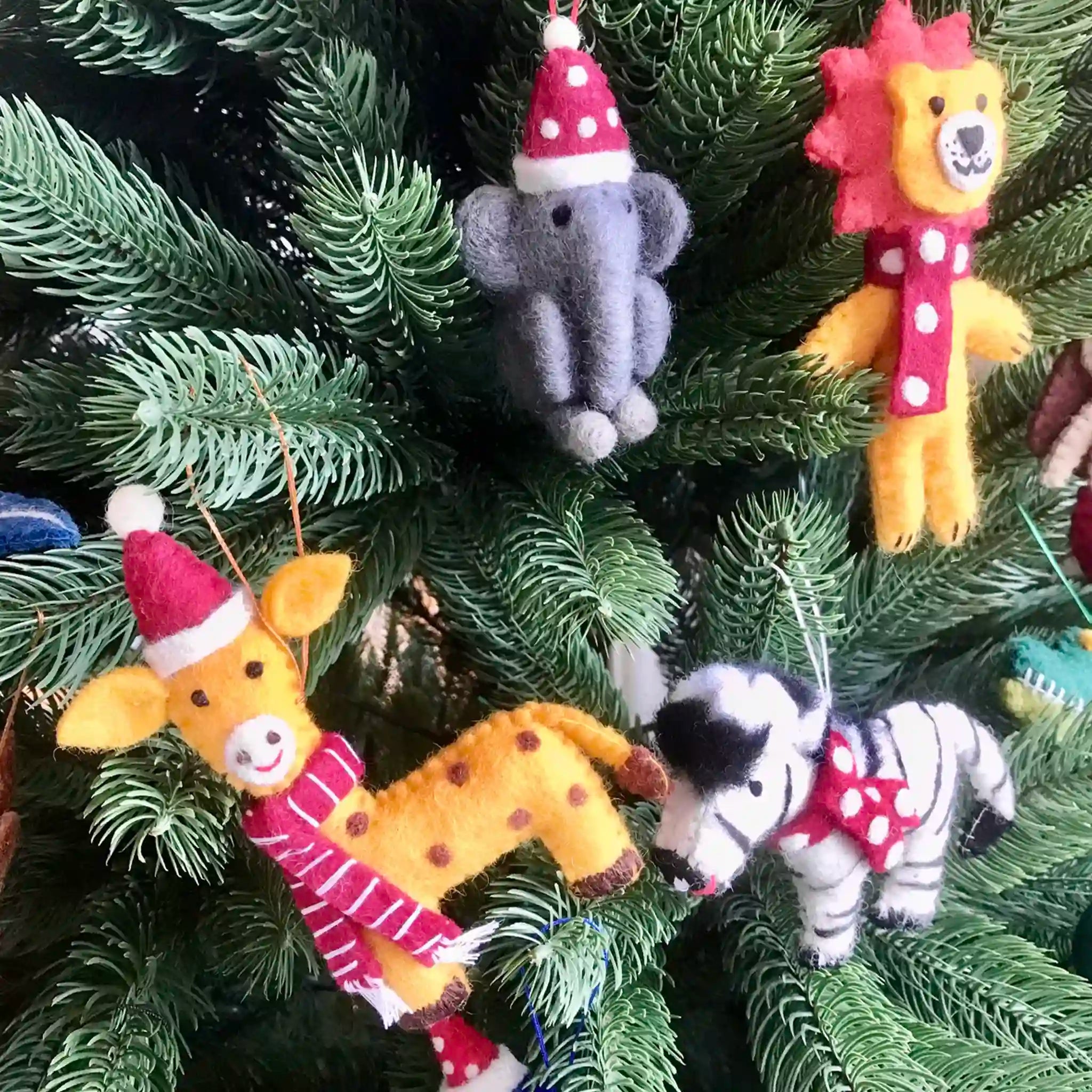 Felt animal Christmas decorations on a tree.