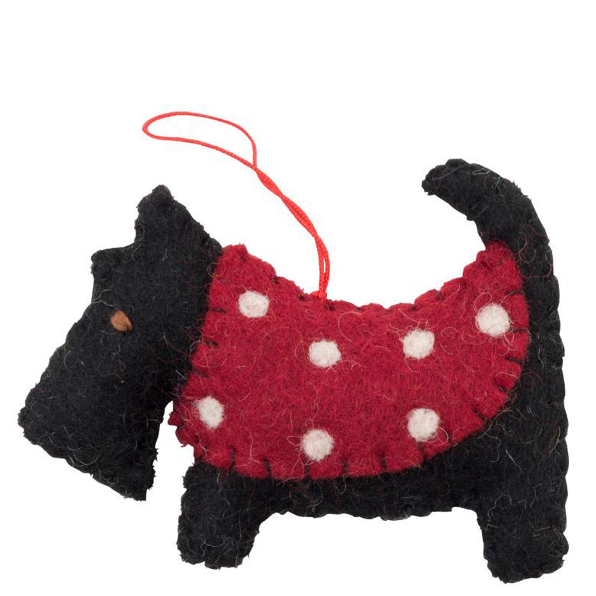 Black dog-shaped ornament with a red polka dot dress on a white background