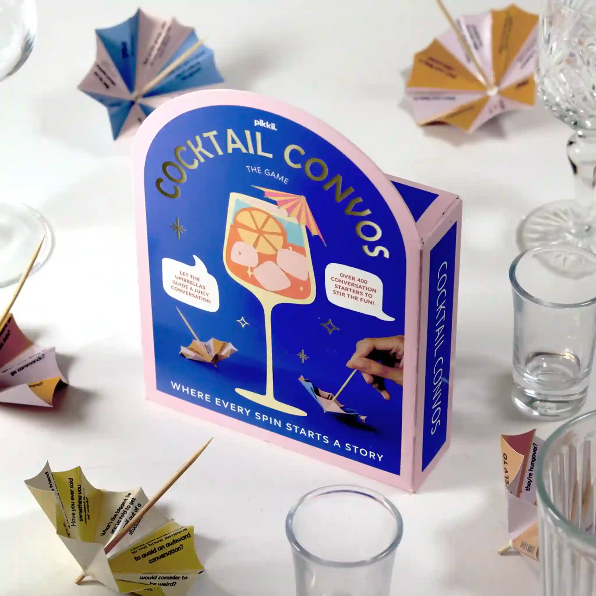 Cocktail Convos game box on a white surface with cocktail glasses and cards.