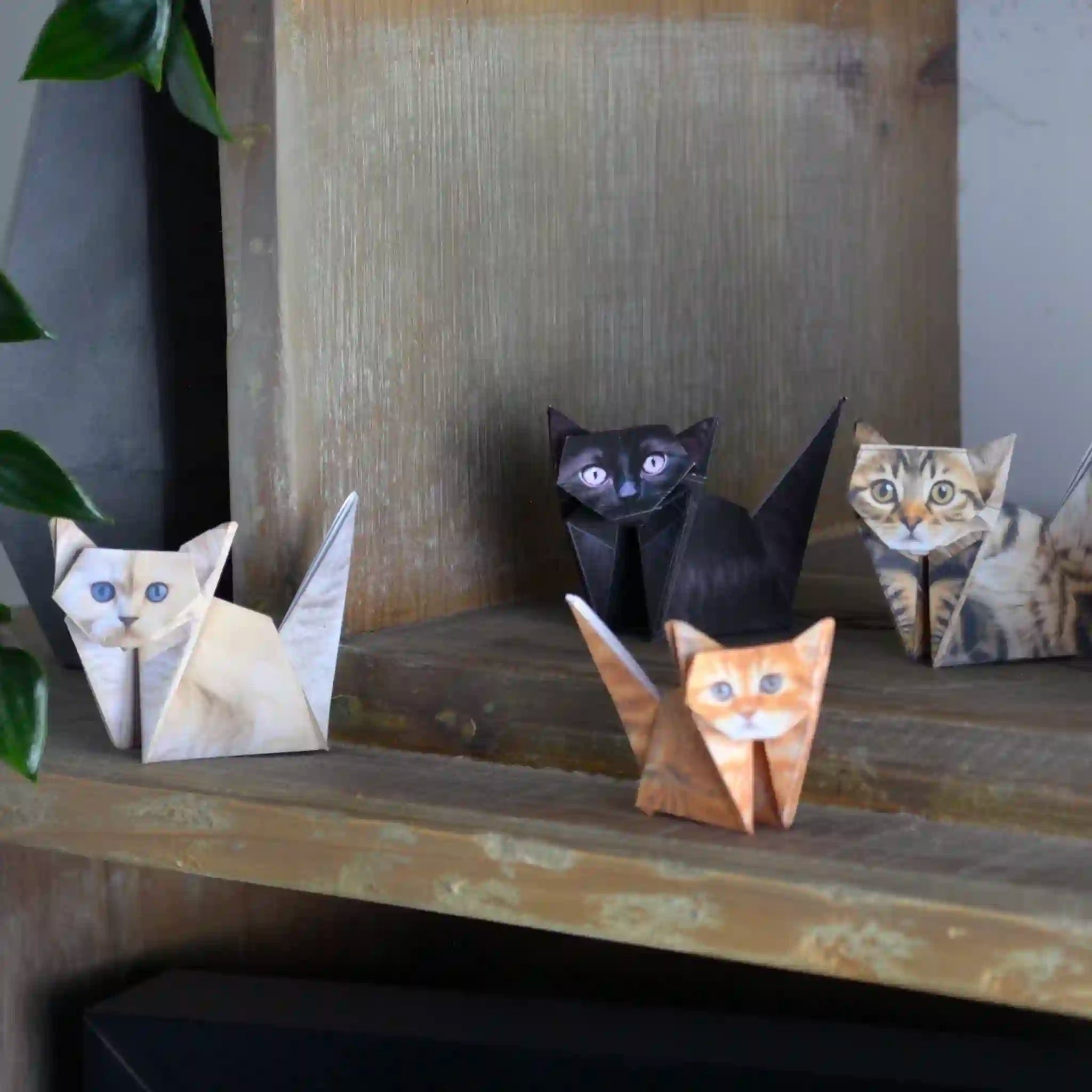 Set of paper cat sculptures on a wooden surface with a neutral background