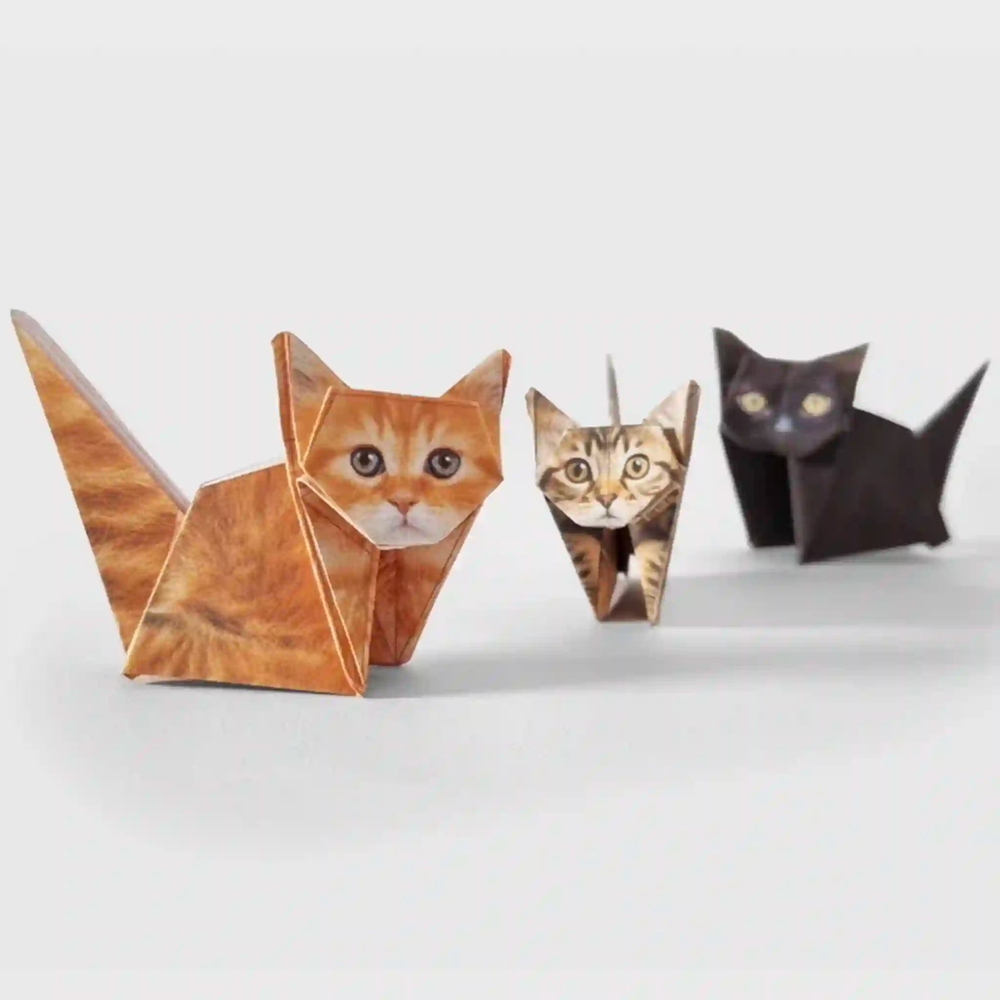 Three origami cats of different colors on a white background