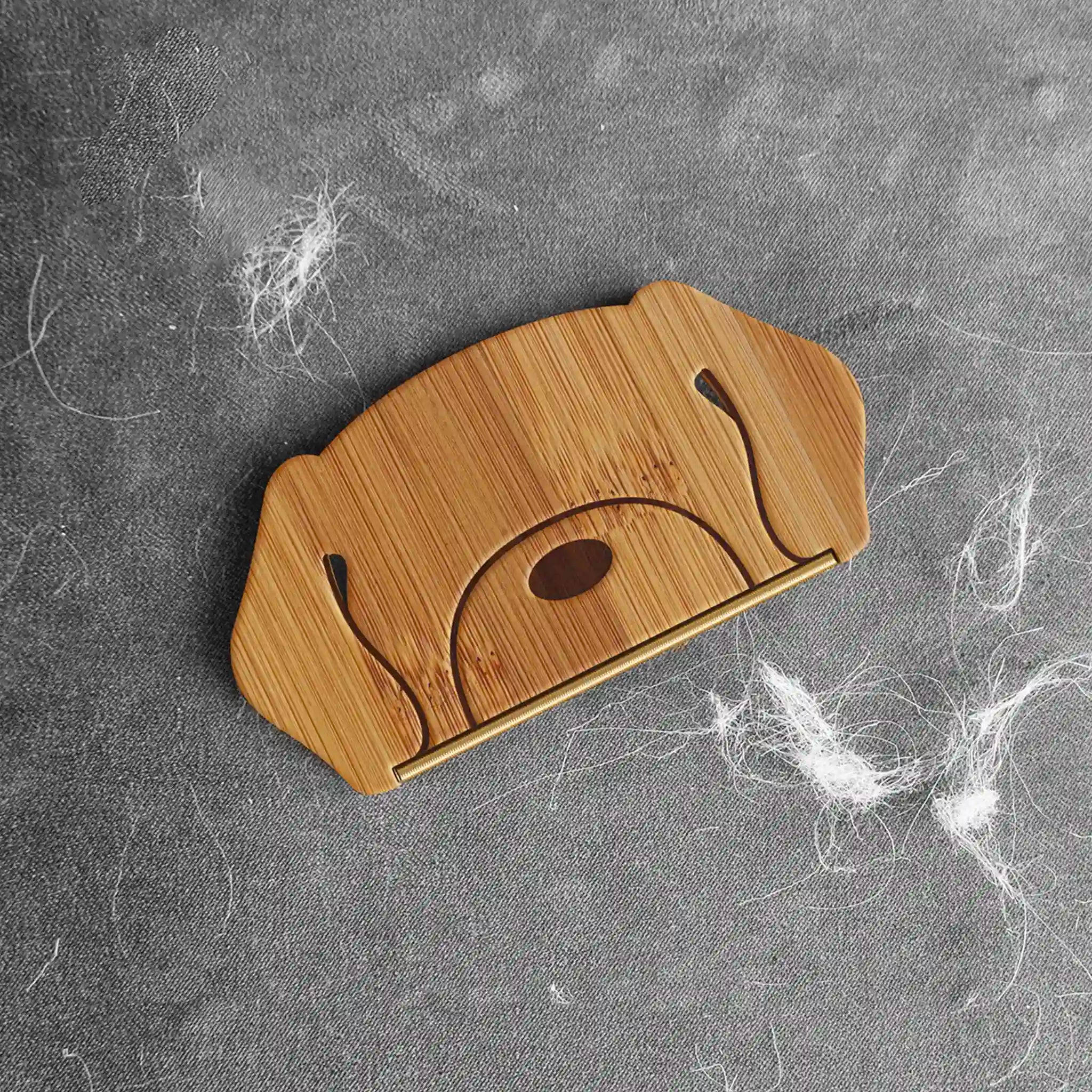 Wooden dog-shaped brush on a gray surface with hair