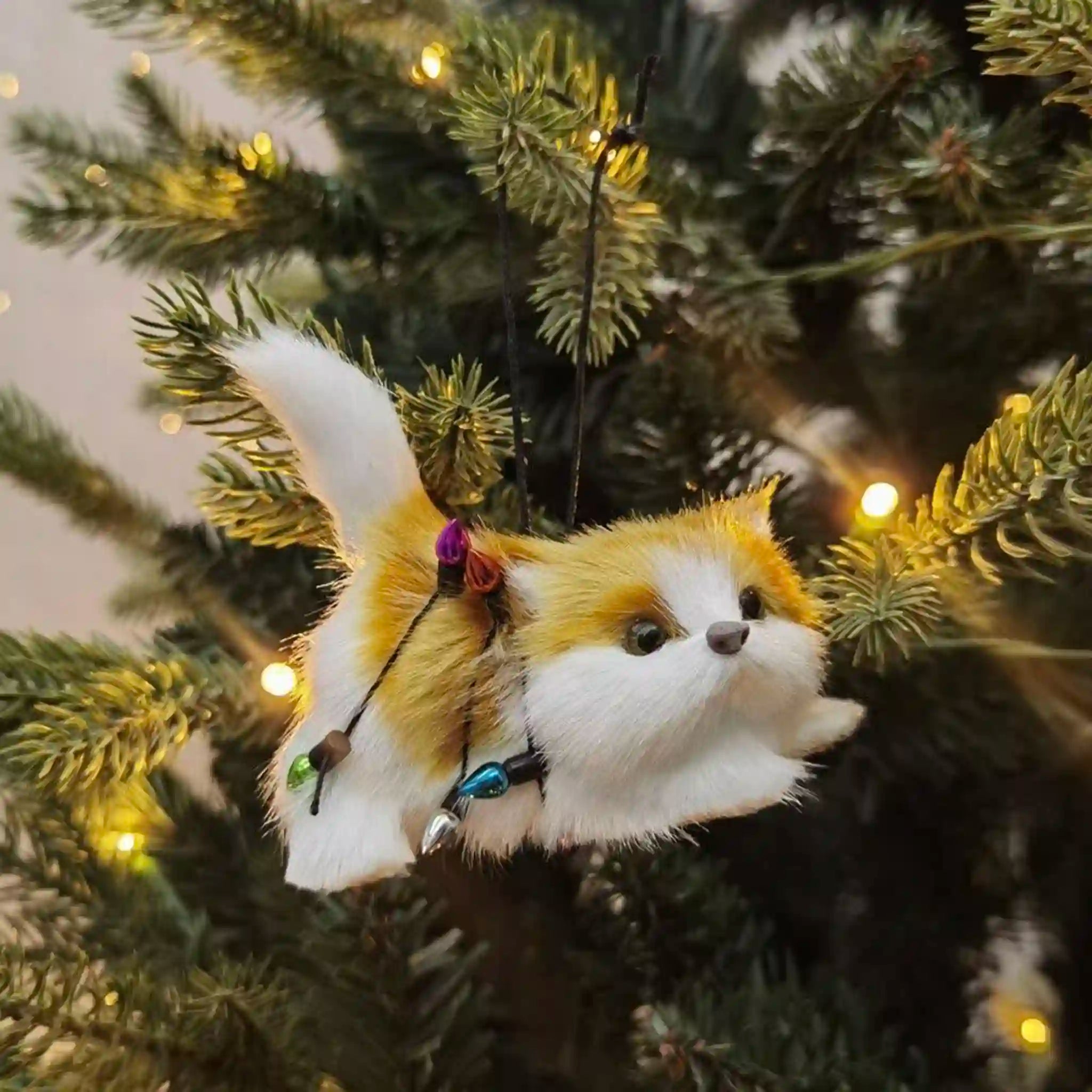 Cat with Christmas lights decoration on a Christmas tree.