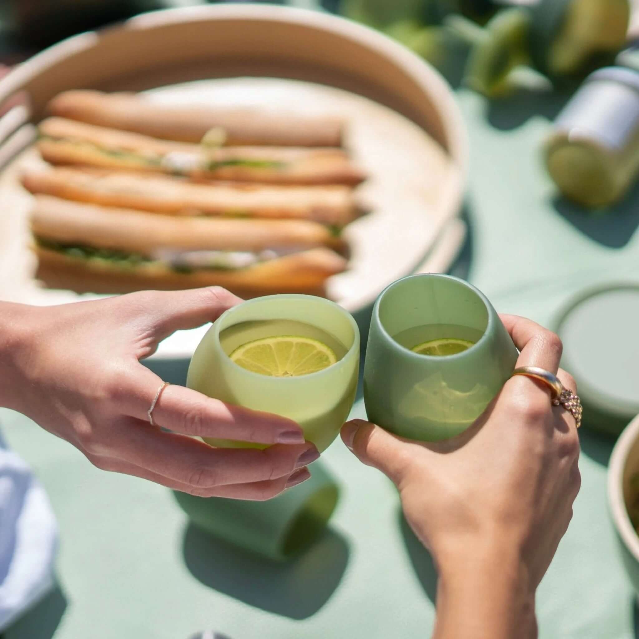 Porter Green Fegg Unbreakable Glass Set - Sage & Olive tumblers held with lemon slices, perfect for outdoor gatherings.