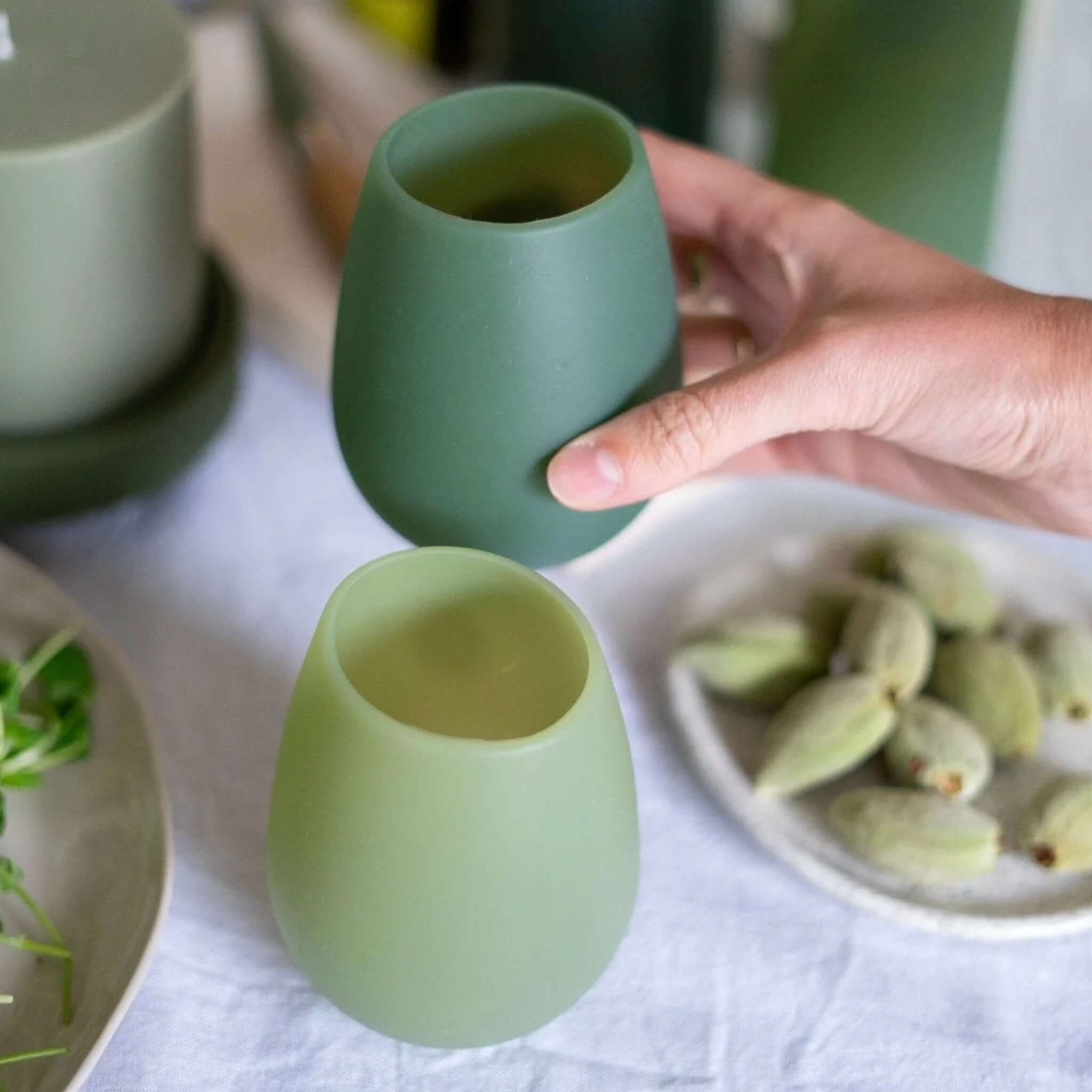 Porter Green Fegg Unbreakable Glass Set - Sage & Olive displayed in hand with two silicone tumblers.