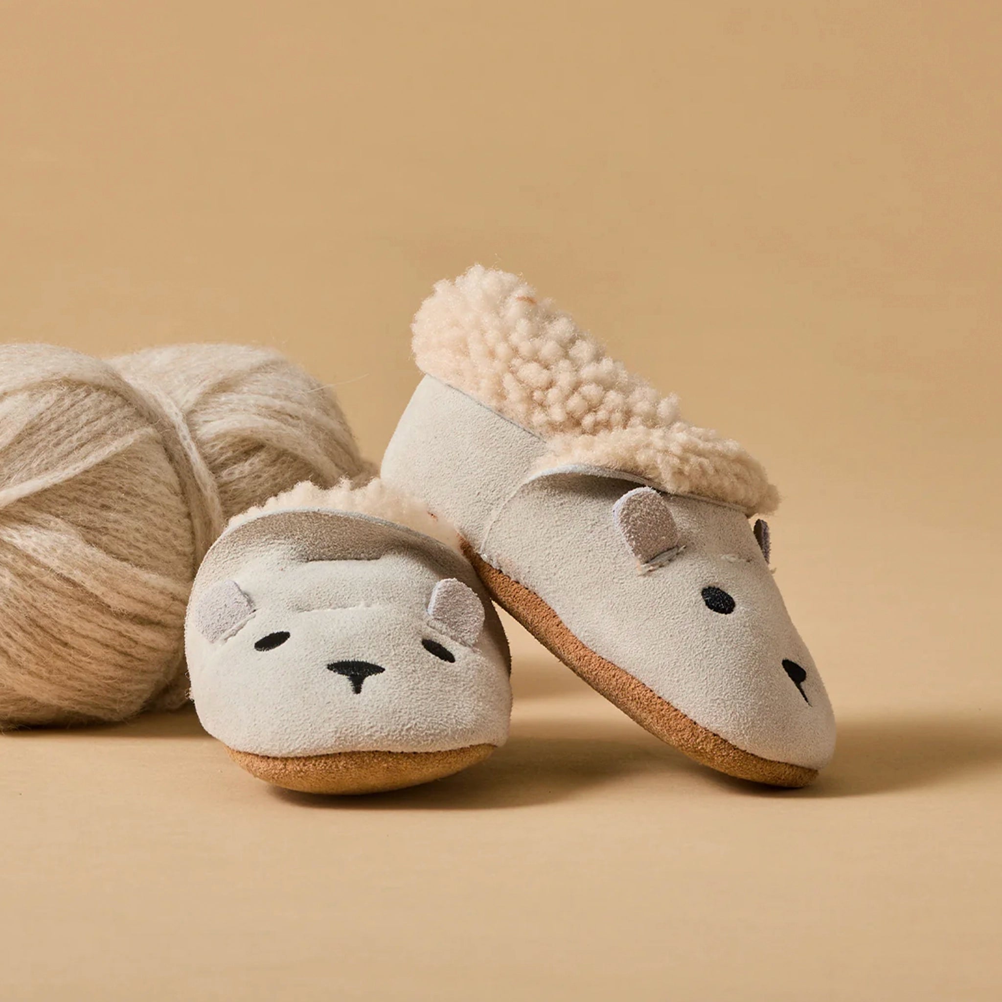 Pair of plush slippers with animal face design on a beige background