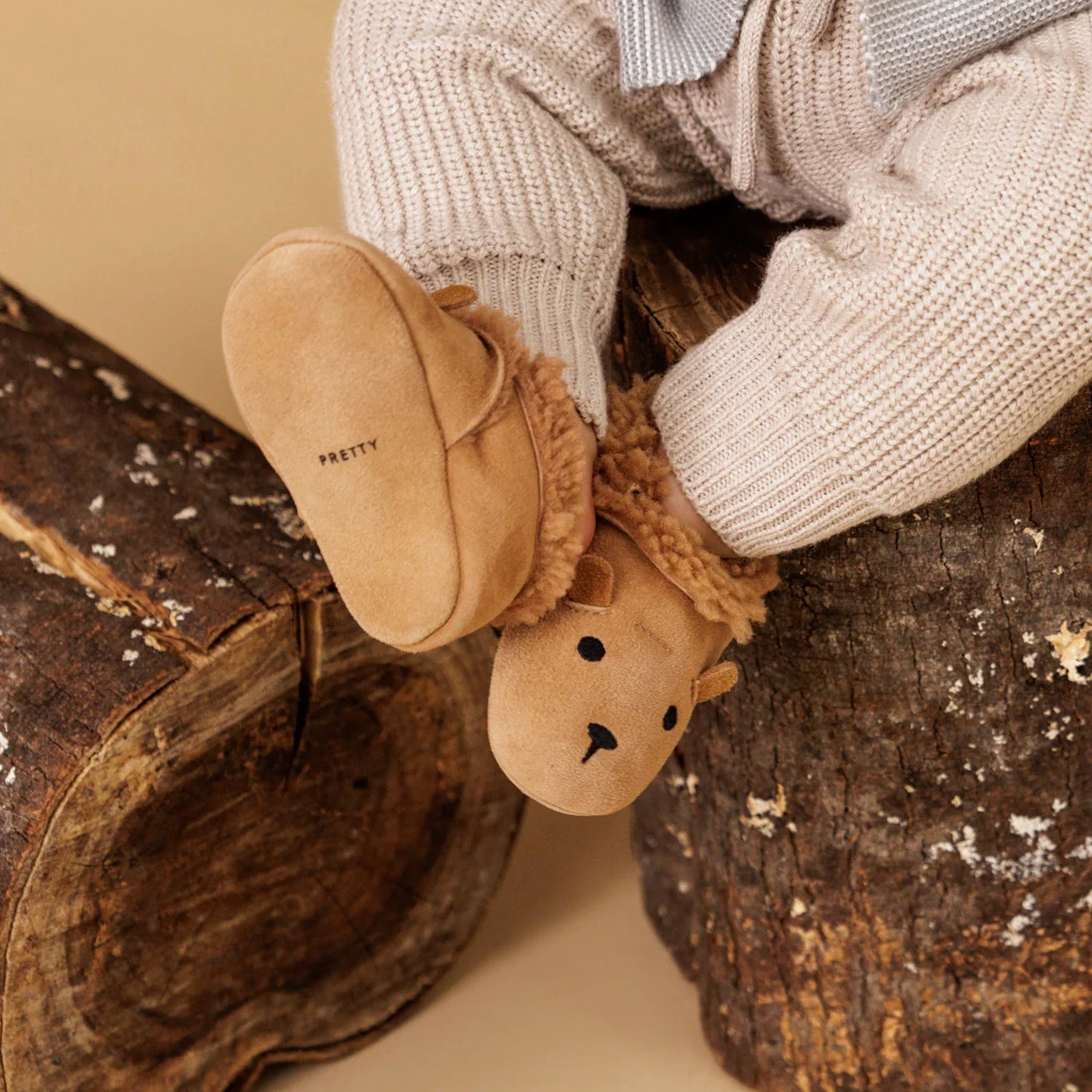 Children's brown slippers with bear design on a wooden surface