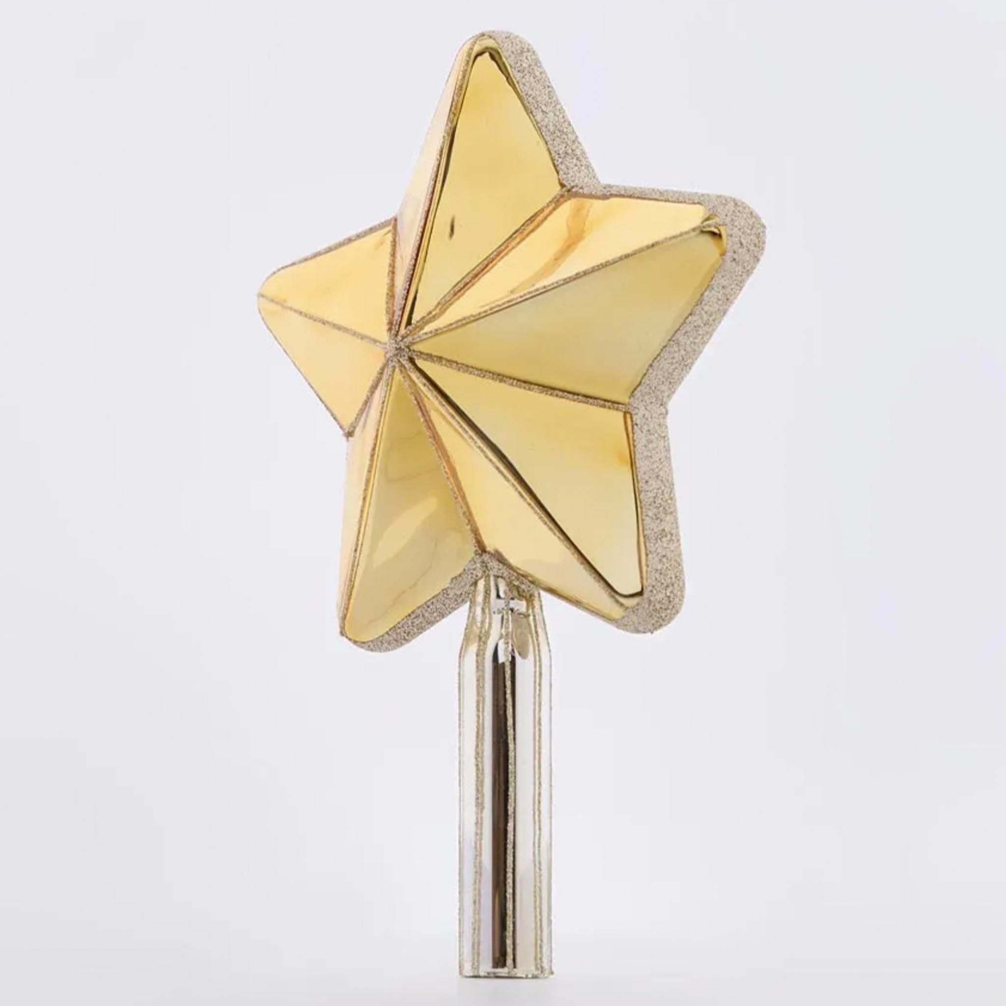 Gold star-shaped tree topper on a grey background