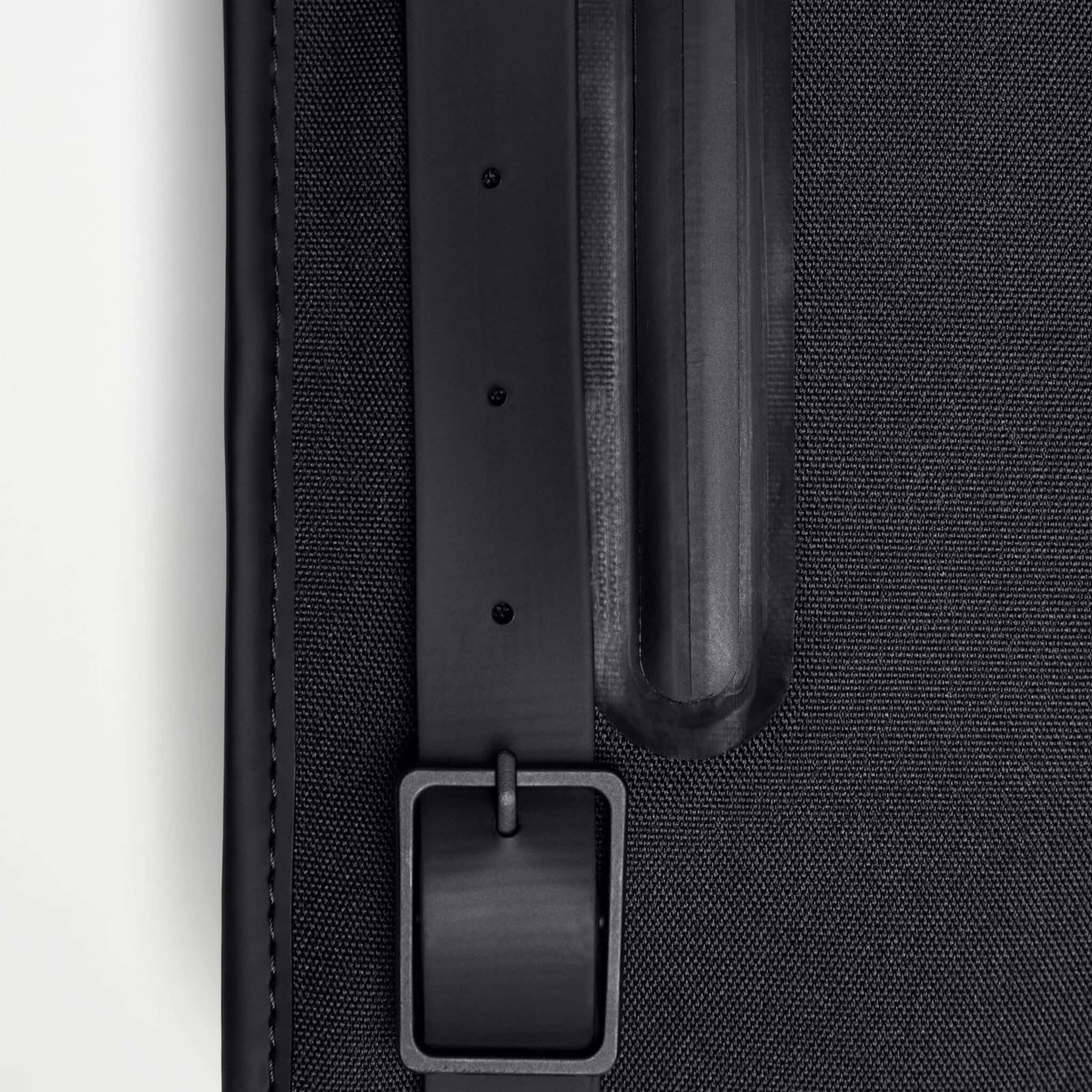 Close-up of the strap and texture of the Rains Backpack Mini - Black, showcasing its sleek design.