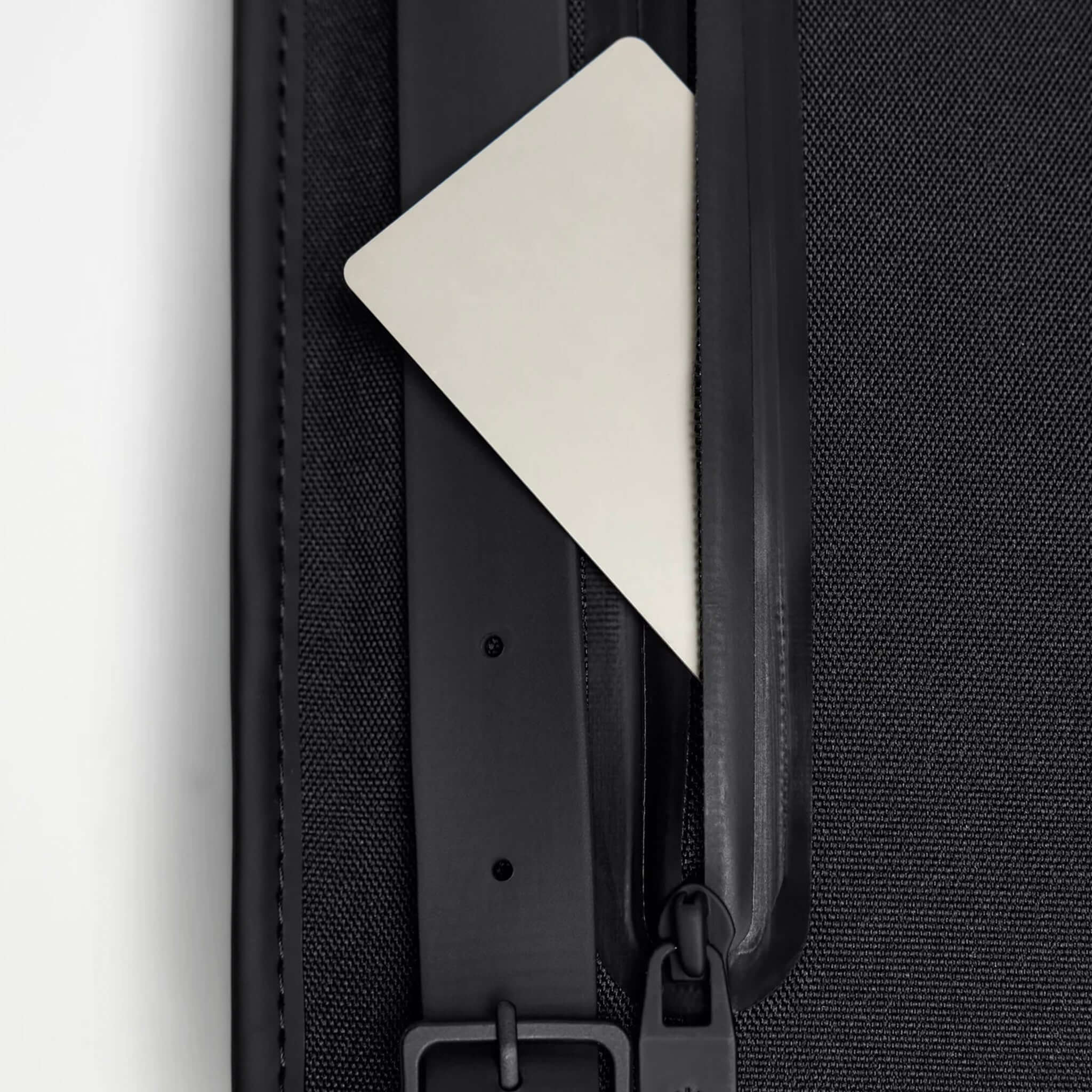 Rains Backpack Mini - Black showing a close-up of the internal pocket with a card.