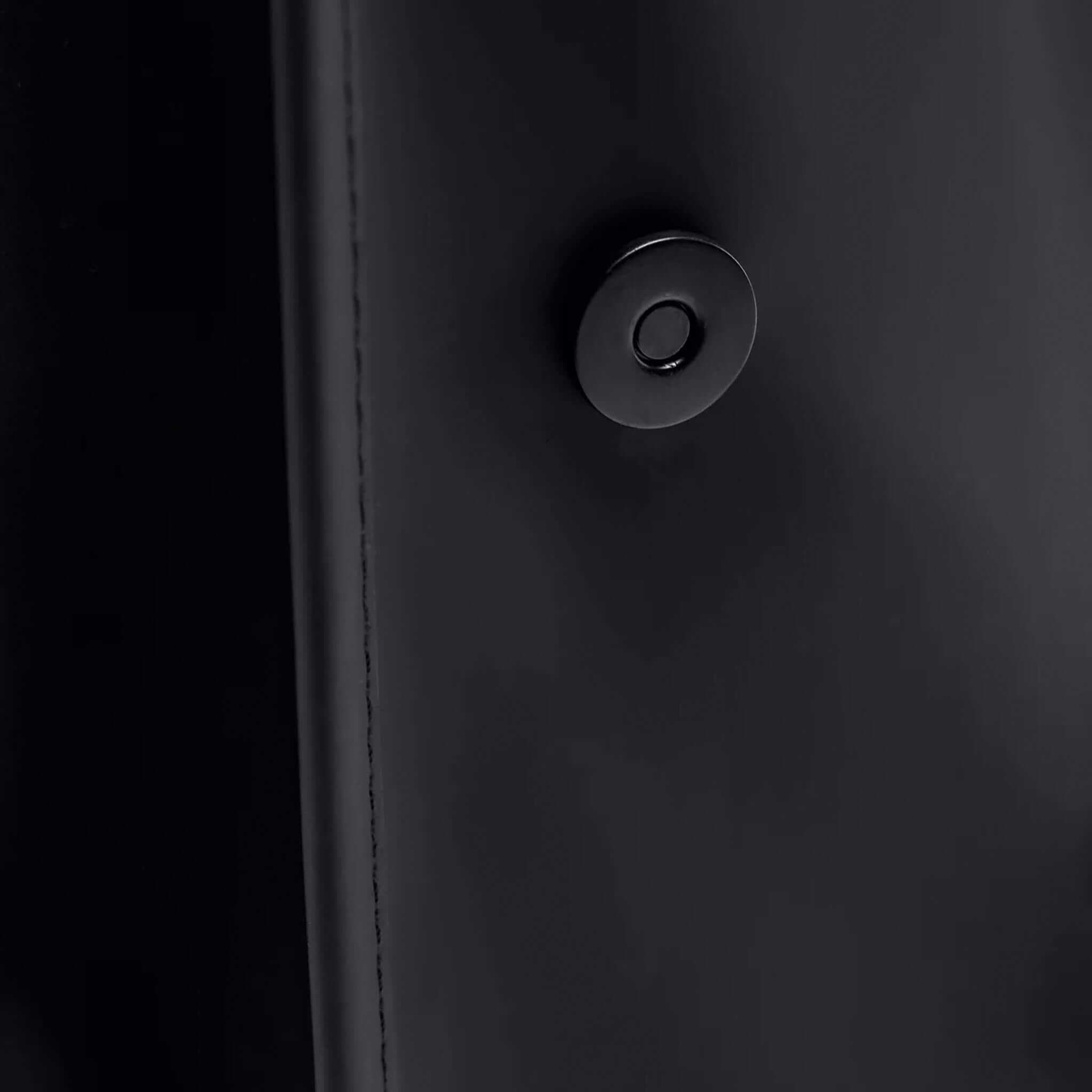 Close-up of the snap fastenings on the Rains Backpack Mini - Black, showcasing its sleek design.
