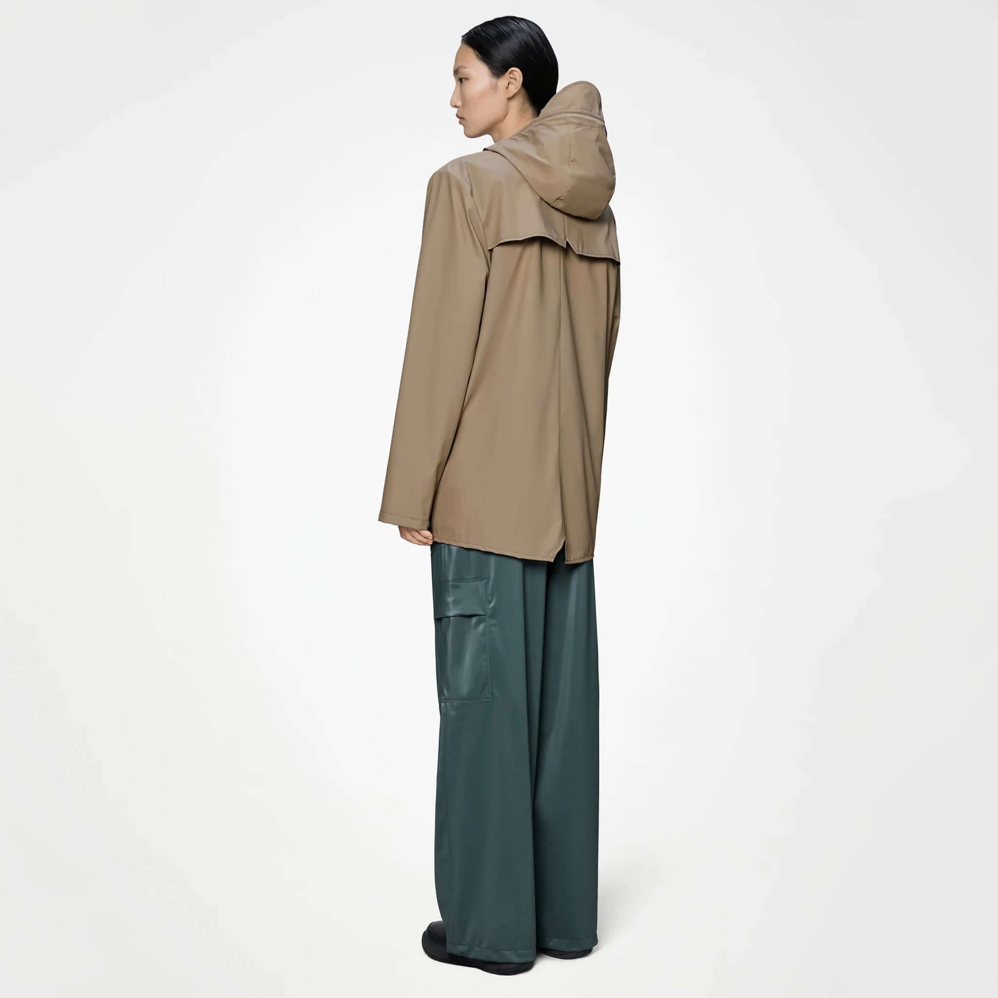 Model wearing the Rains Jacket - Beige from the back, showcasing its minimalist design and adjustable hood.
