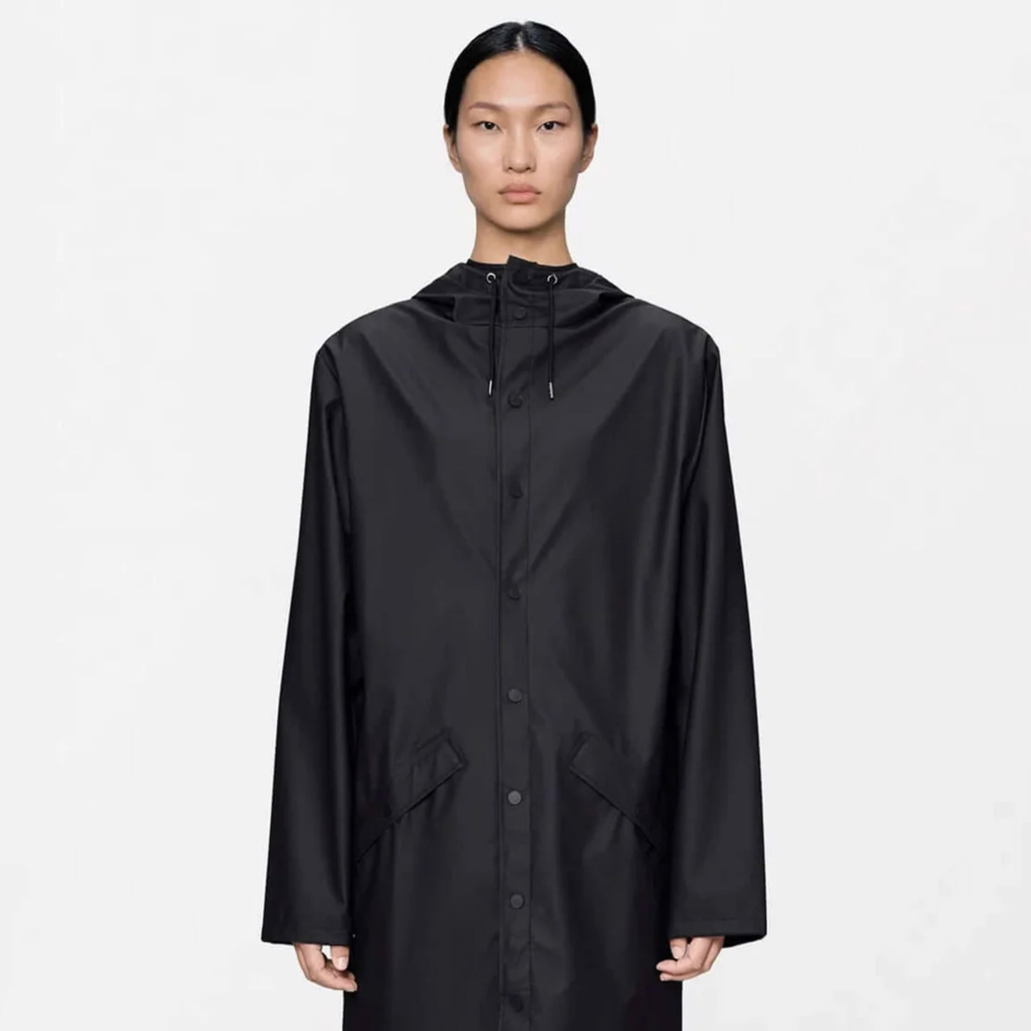 Rains Long Jacket - Black displayed on a model, featuring a minimalistic design and adjustable hood.