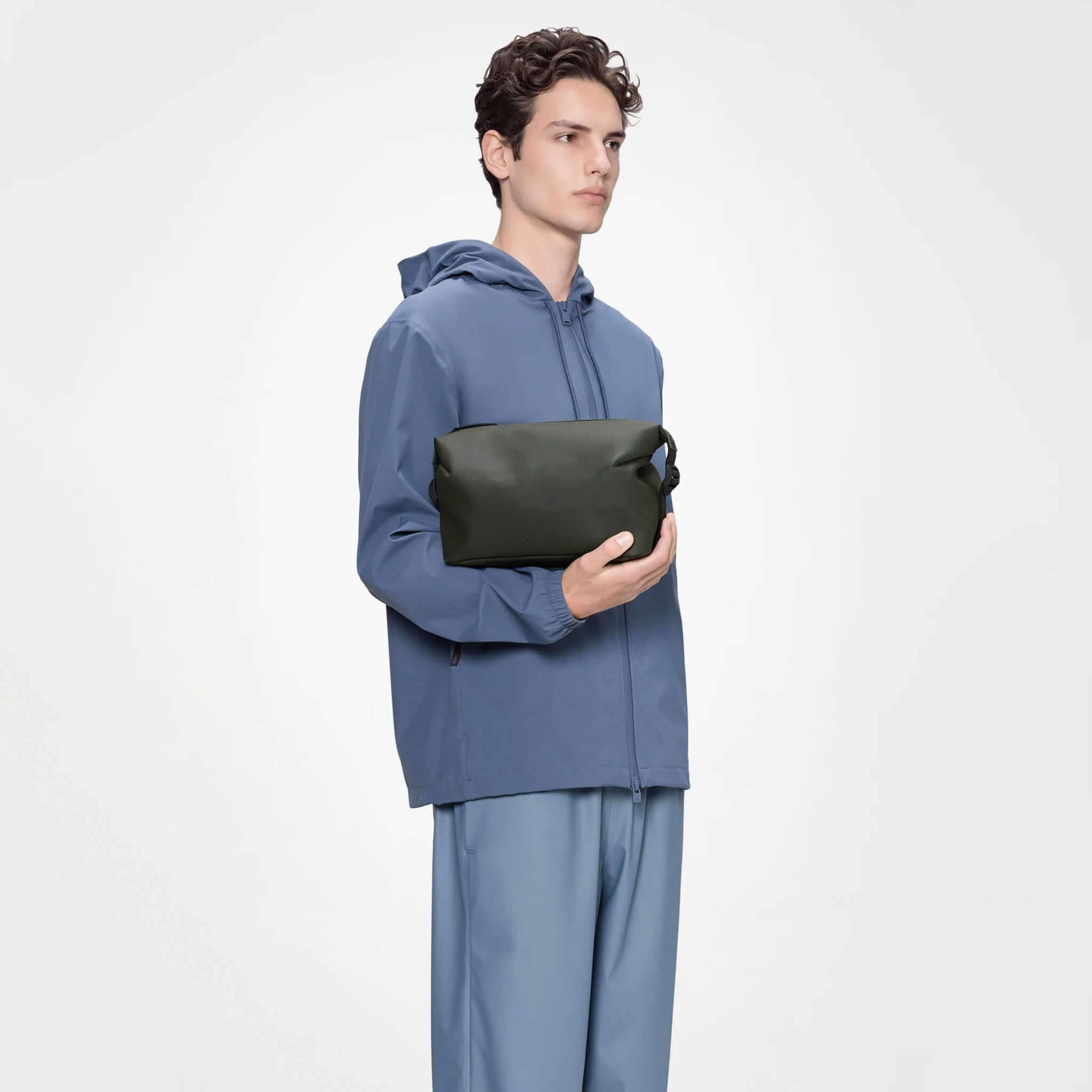 Man holding Rains Wash Bag Small - Green, a stylish and waterproof toiletry bag.