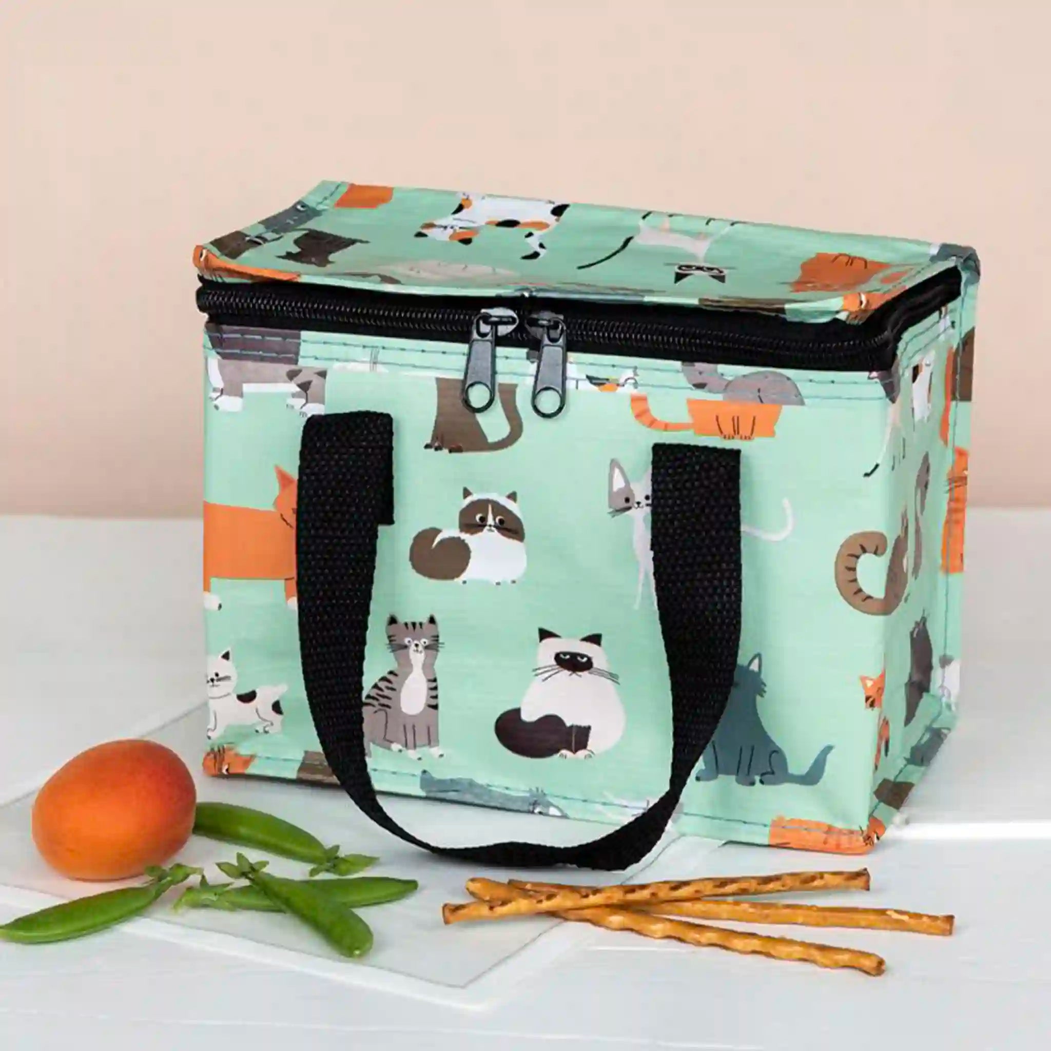 Cooler bag with cat pattern on a white surface with snacks