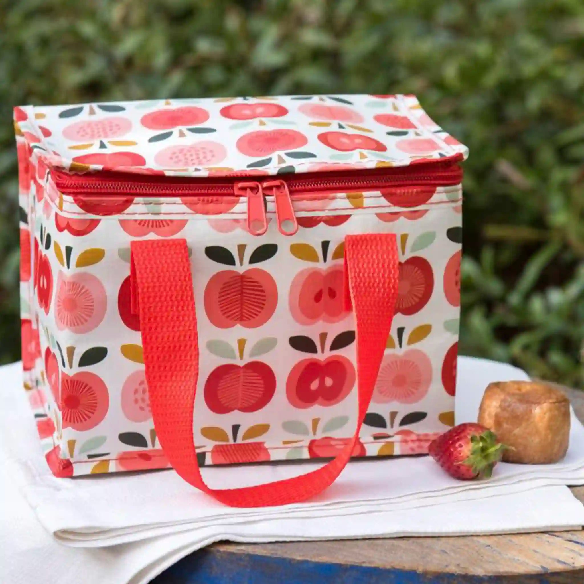 Insulated lunch bag with apple pattern on a table outdoors